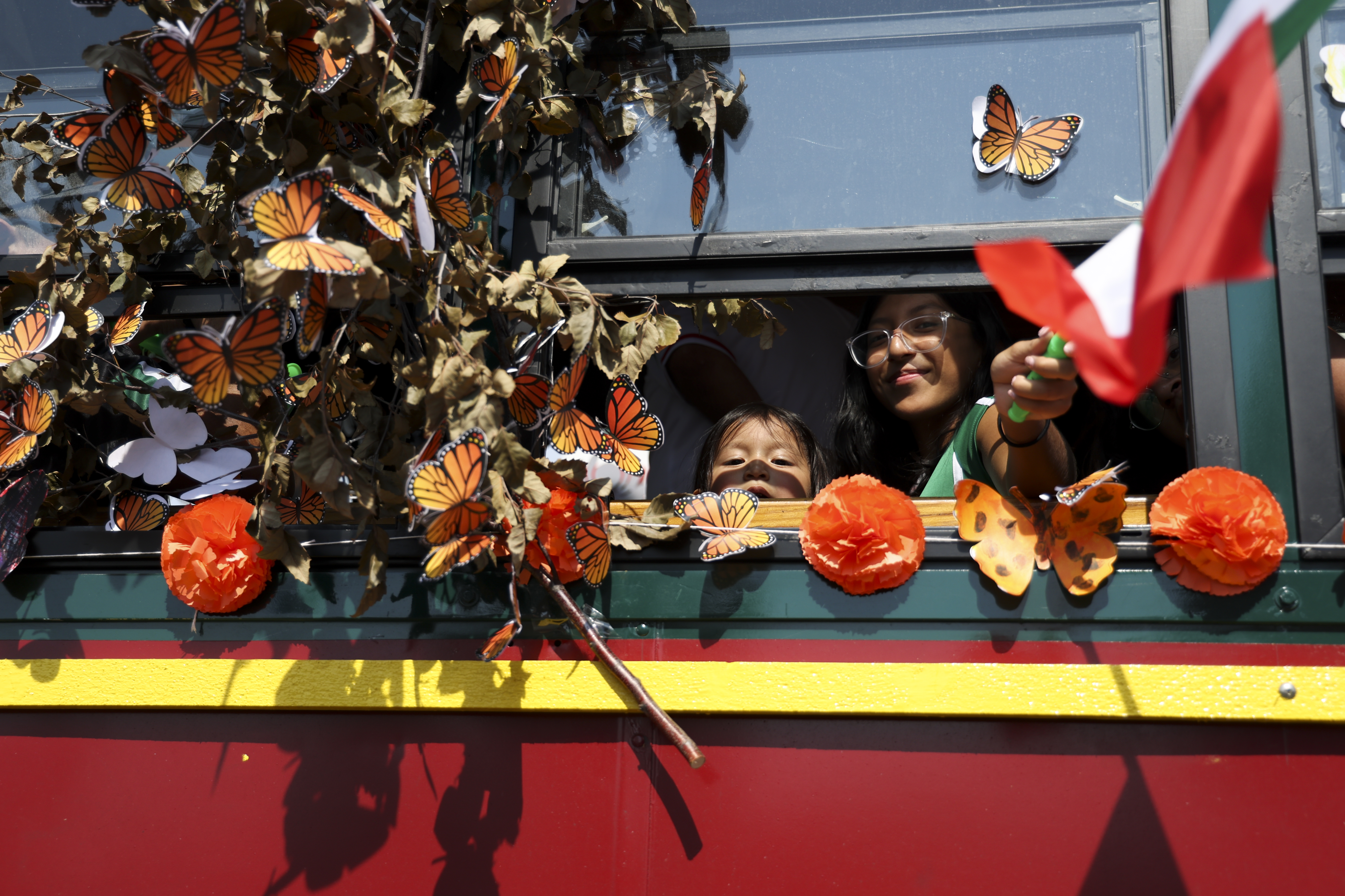 A person waves a flag through the window of the El Valor trolley during the Mexican Independence Day Parade in Little Village on Sunday, Sept. 15, 2024. (Eileen T. Meslar/Chicago Tribune)