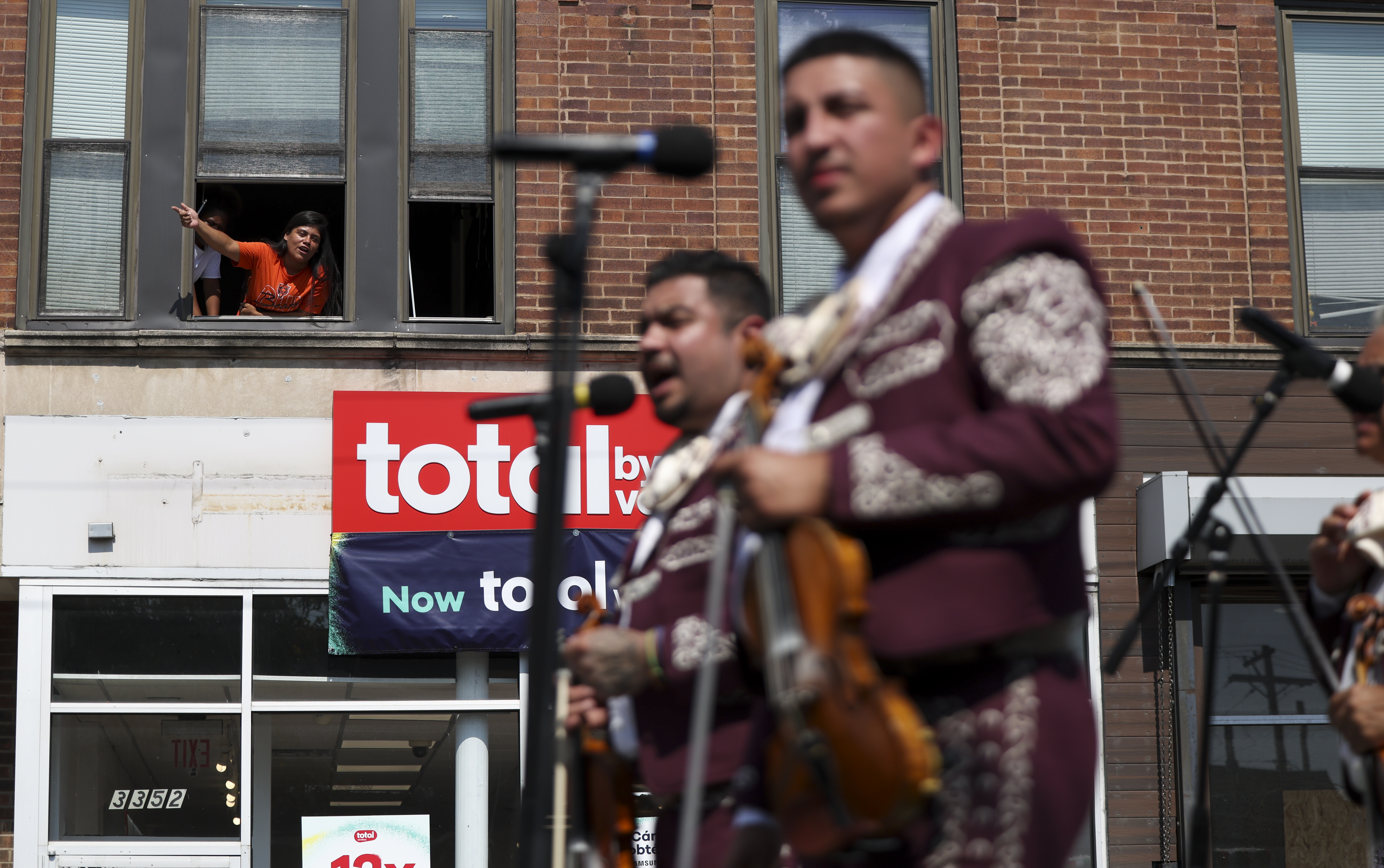 A woman in a window sings as a Mariachi band performs during the Mexican Independence Day Parade in Little Village on Sunday, Sept. 15, 2024. (Eileen T. Meslar/Chicago Tribune)