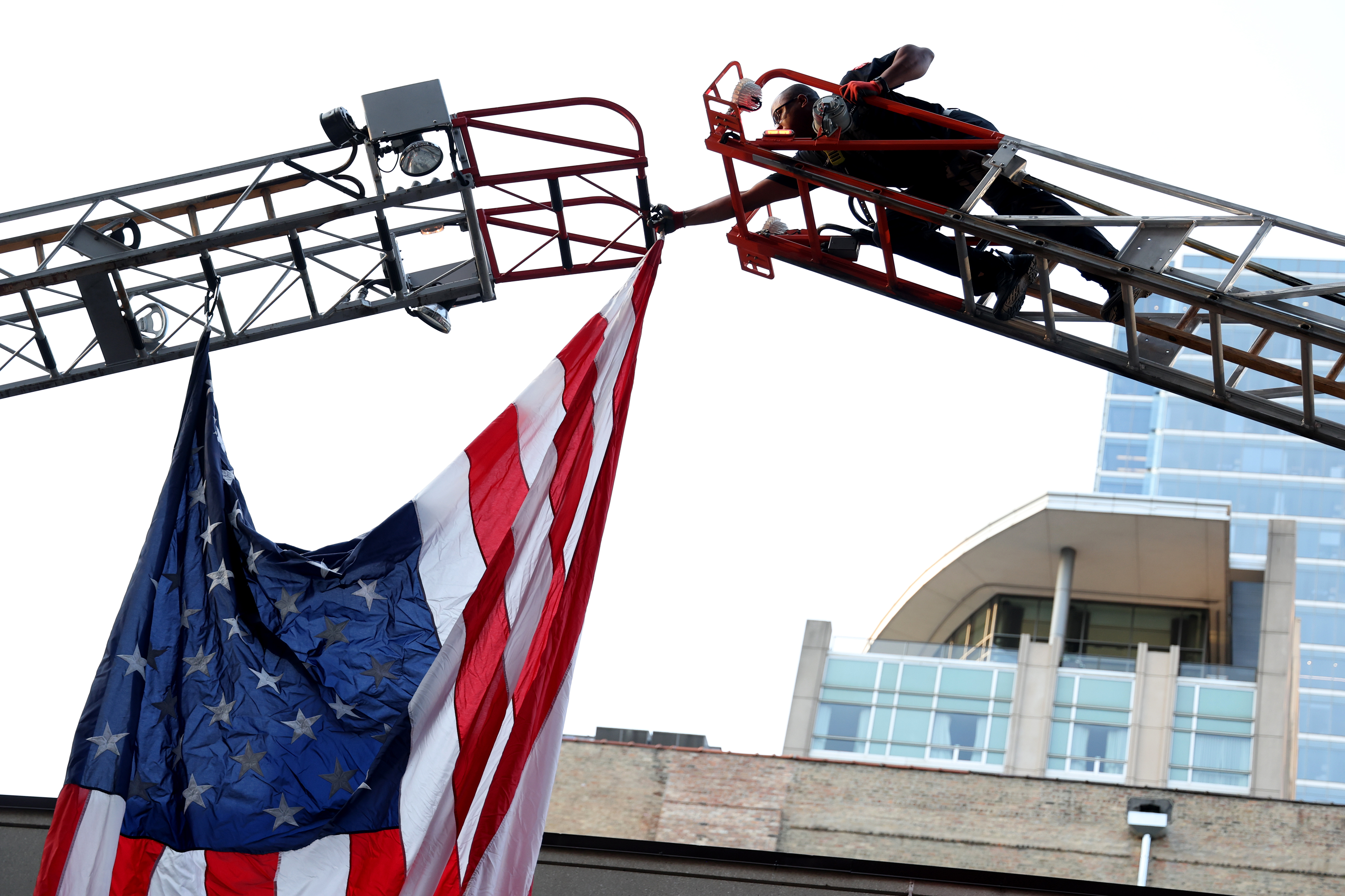 Firefighter Donald York Jr. puts up the American flag across two ladder trucks as the Chicago Fire Department marks the 23rd anniversary of the 9/11 terrorist attacks on Sept. 11, 2024, outside the Engine 42 fire station in Chicago. (Antonio Perez/Chicago Tribune)