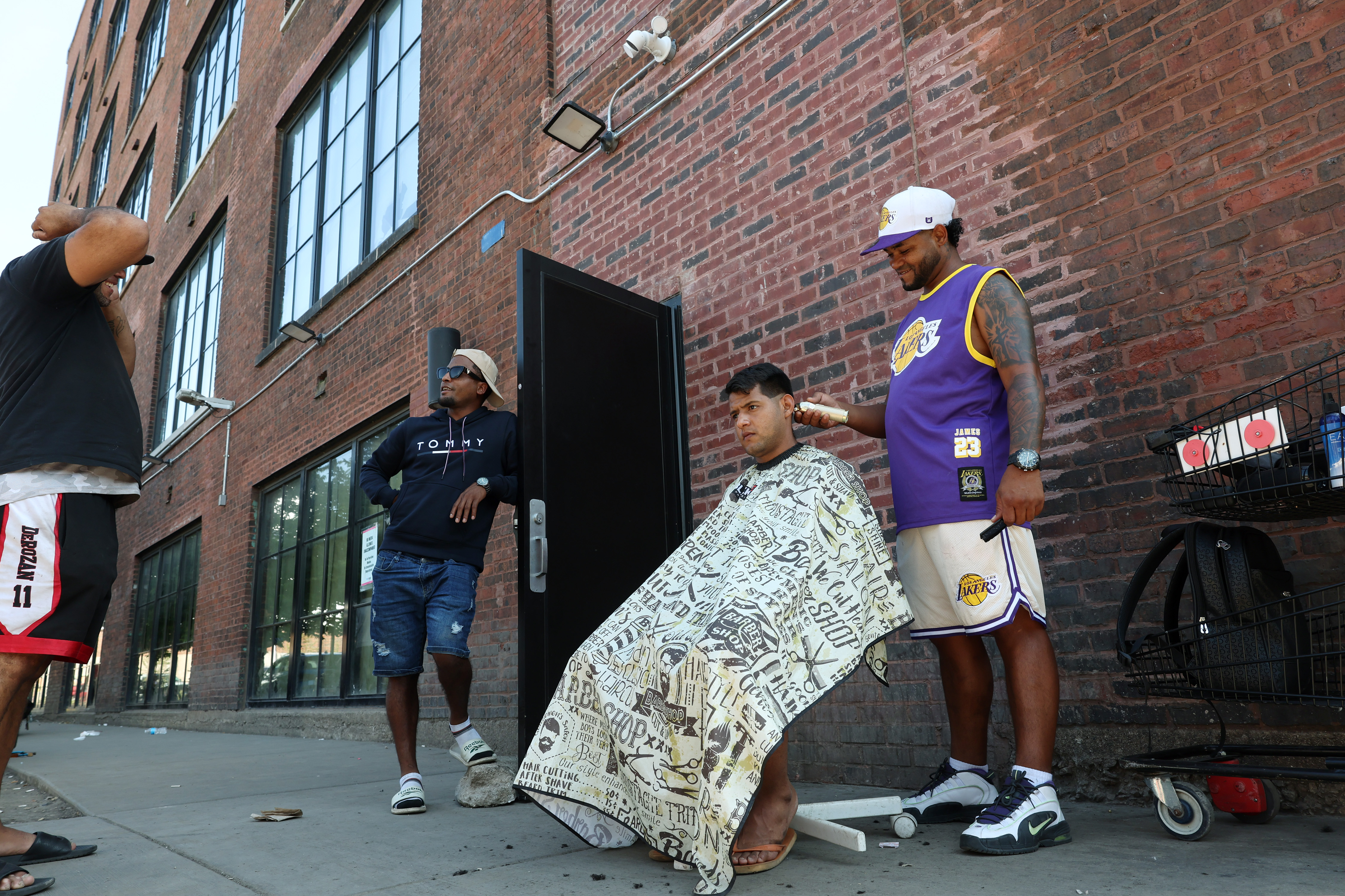 A barber named Javier, last name not given, gives a haircut to a man named Jorge, last name not given, outside a migrant shelter in the 1300 block of North Elston Avenue on Thursday, Sept. 19, 2024, in Chicago. (John J. Kim/Chicago Tribune)