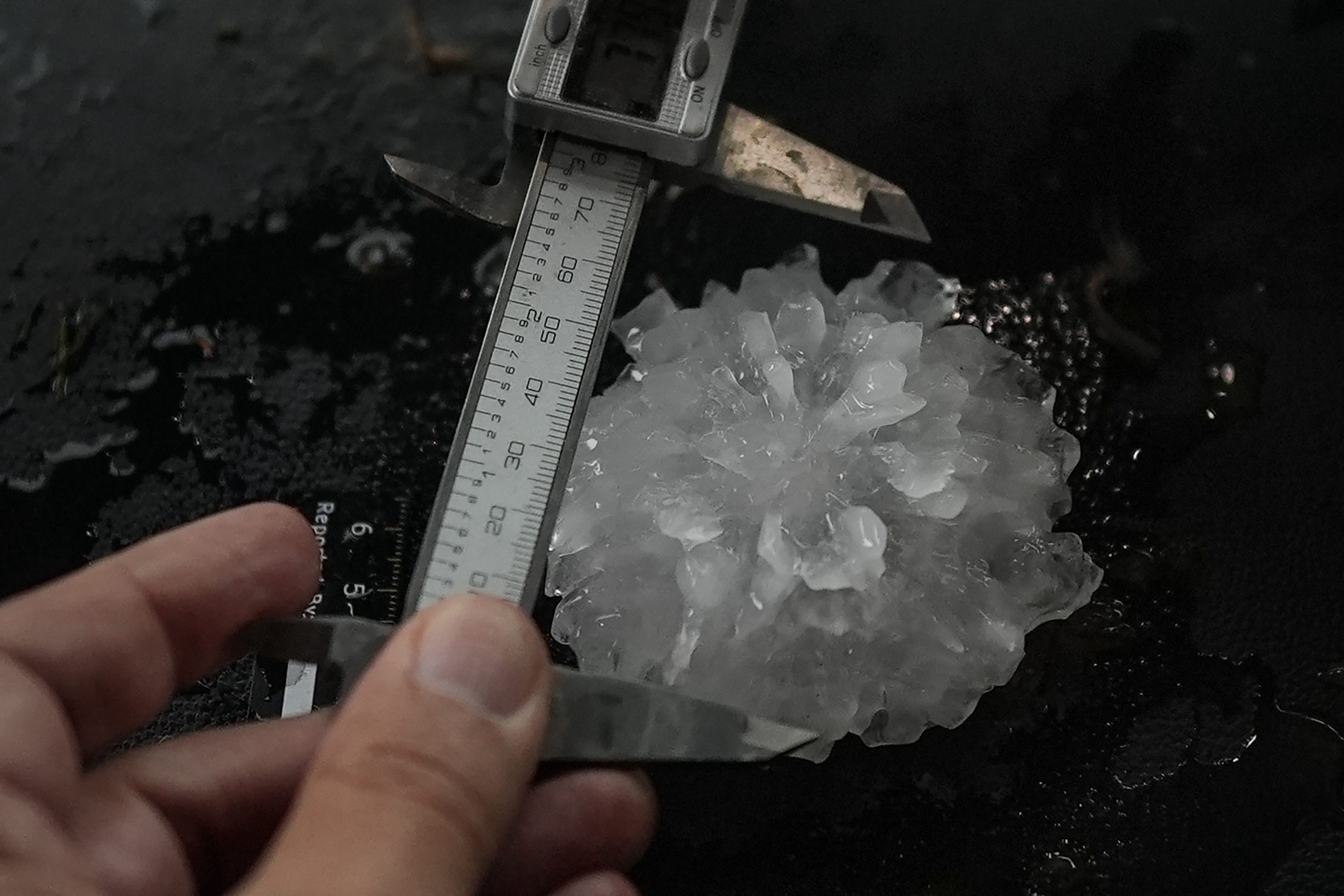 Forensic engineer Tim Marshall measure a large hail in the front seats of Northern Illinois University's Husky Hail Hunter during a Project ICECHIP operation, June 6, 2025, in Morton, Texas. Project ICECHIP is made of teams from several universities observing storms from the inside and seeing how the hail forms. (Carolyn Kaster/AP)