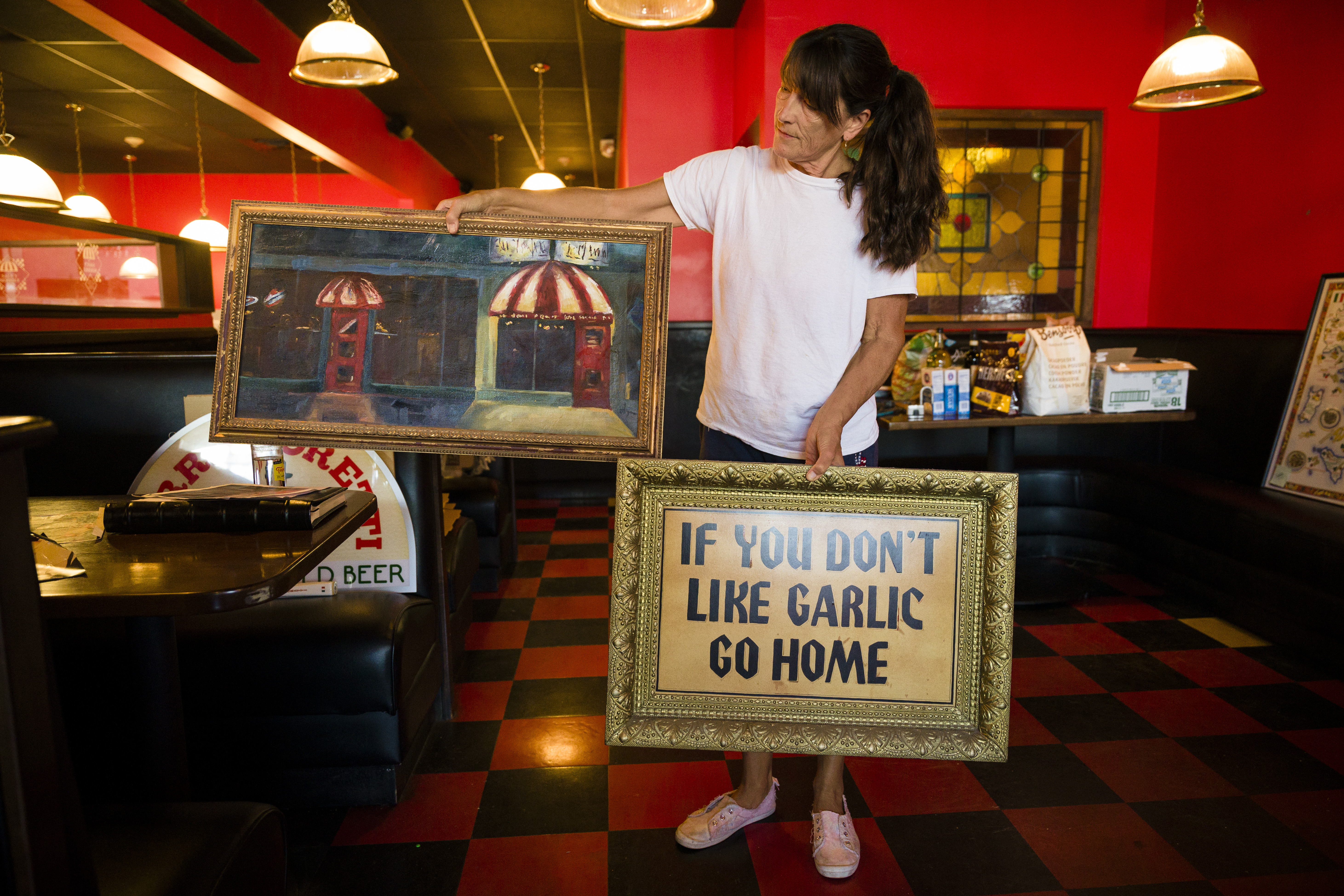 Theresa Reynolds, a longtime server at the restaurant The Saucy Noodle, holds the Denver restaurant's memorabilia during the restaurant's "moving sale" Wednesday, Aug. 17, 2022. The restaurant ??