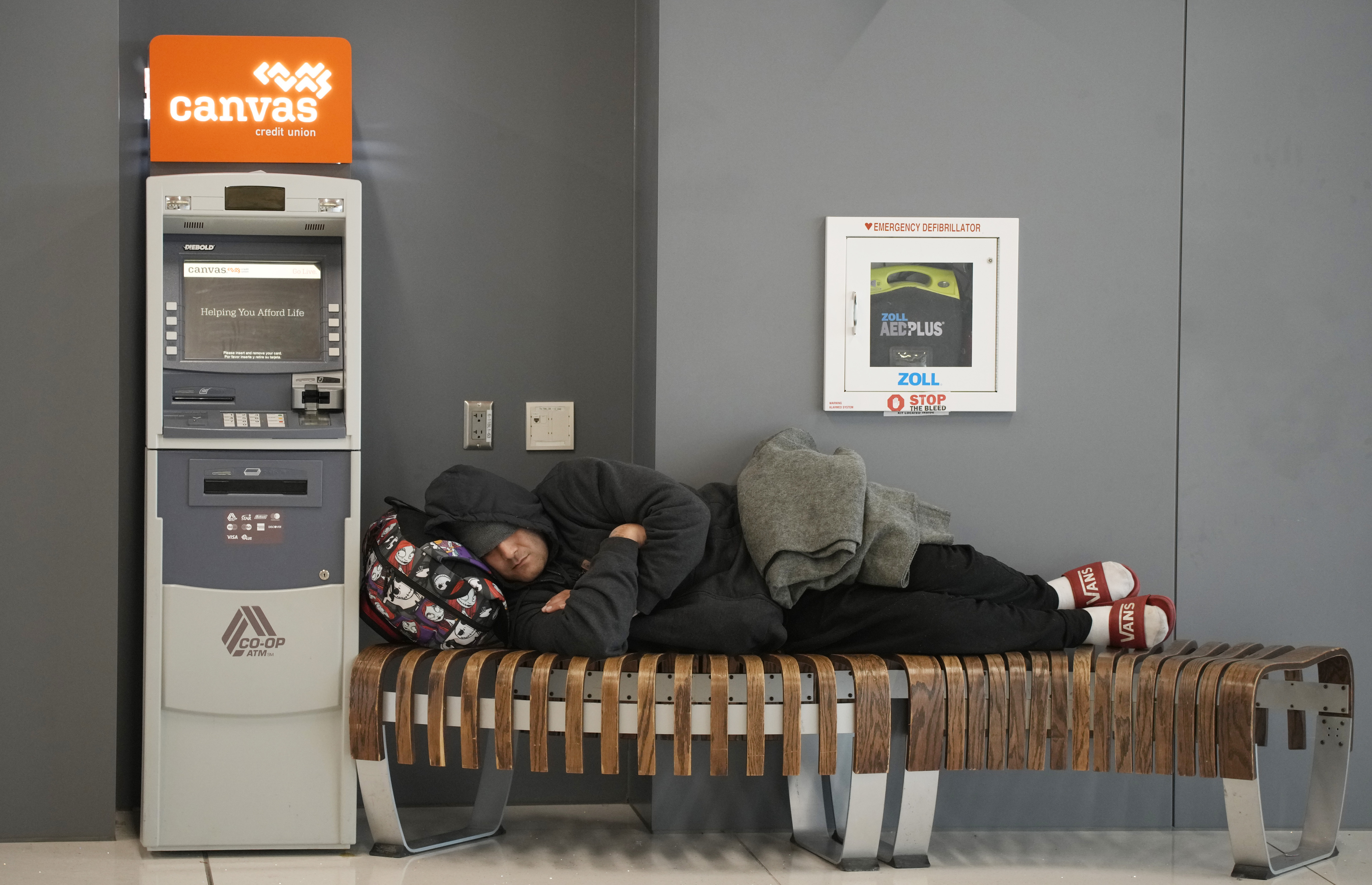 A traveler sleeps on a bench near the Southwest Airlines check-in counter at Denver International Airport, Tuesday, Dec. 27, 2022, in Denver. (AP Photo/David Zalubowski)