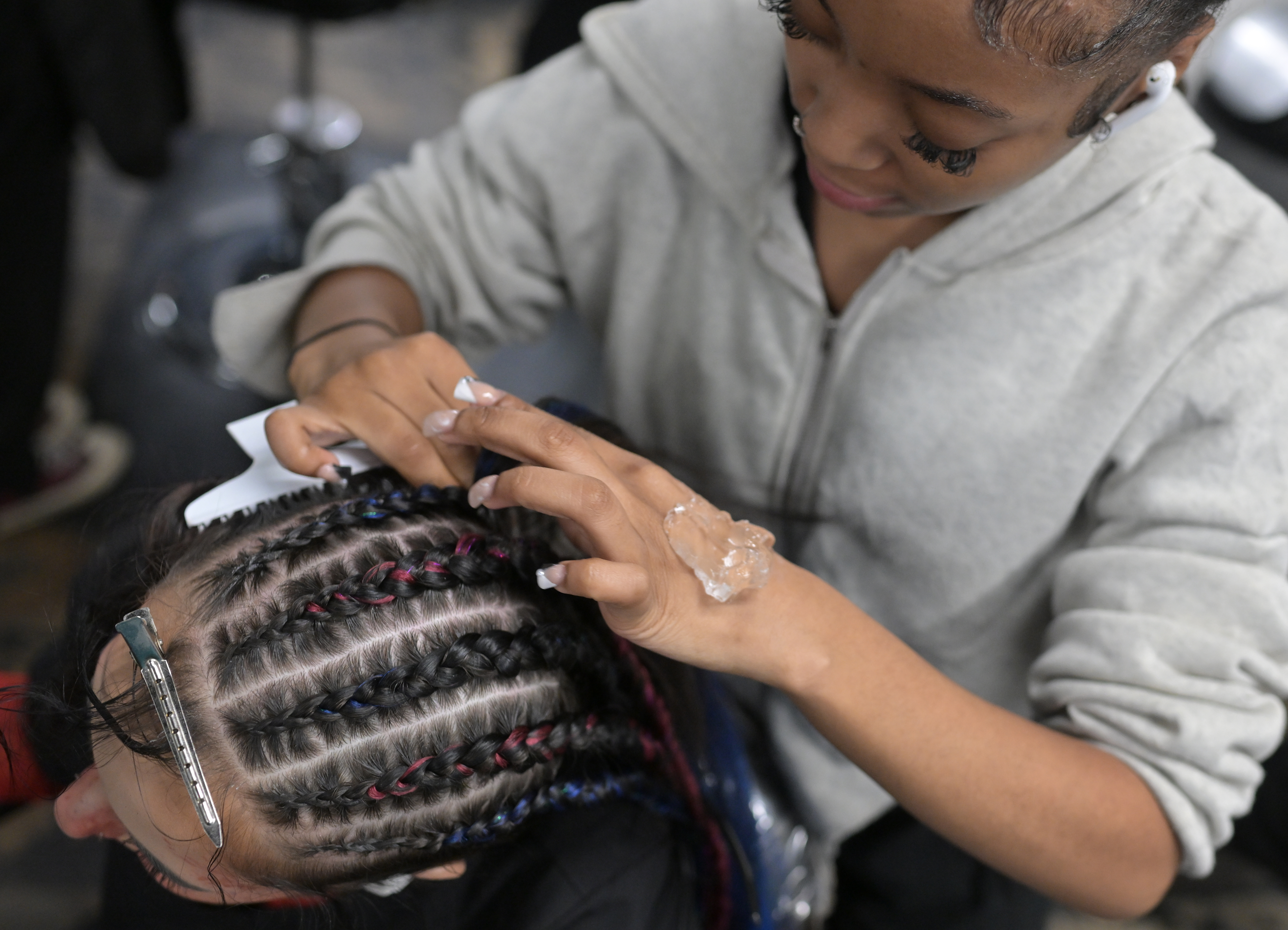 Emily Griffith Technical College student eighteen-year-old Zaahara Domio, top, works on her cosmetology skills as she does the hair of her fellow student Chloe Hill, 20, during class in Denver on May 30, 2024. (Photo by RJ Sangosti/The Denver Post)