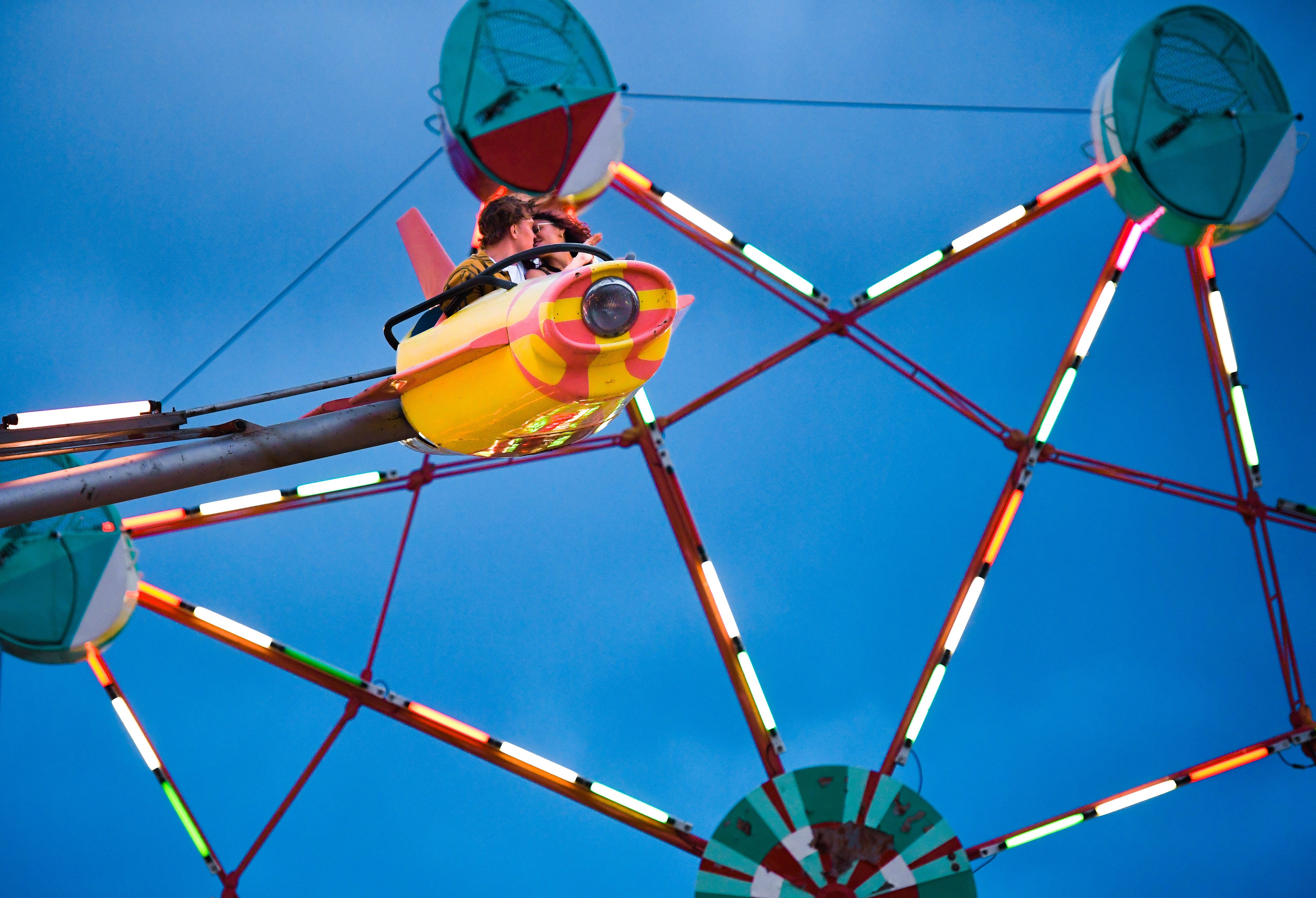 Colton Chorpenning (left) and Brie Rios share a kiss as they fly through the air on the Satellite ride at Lakeside Amusement Park in Lakeside, Colorado on Thursday, June 27, 2024. (Photo by Zachary Spindler-Krage/The Denver Post)