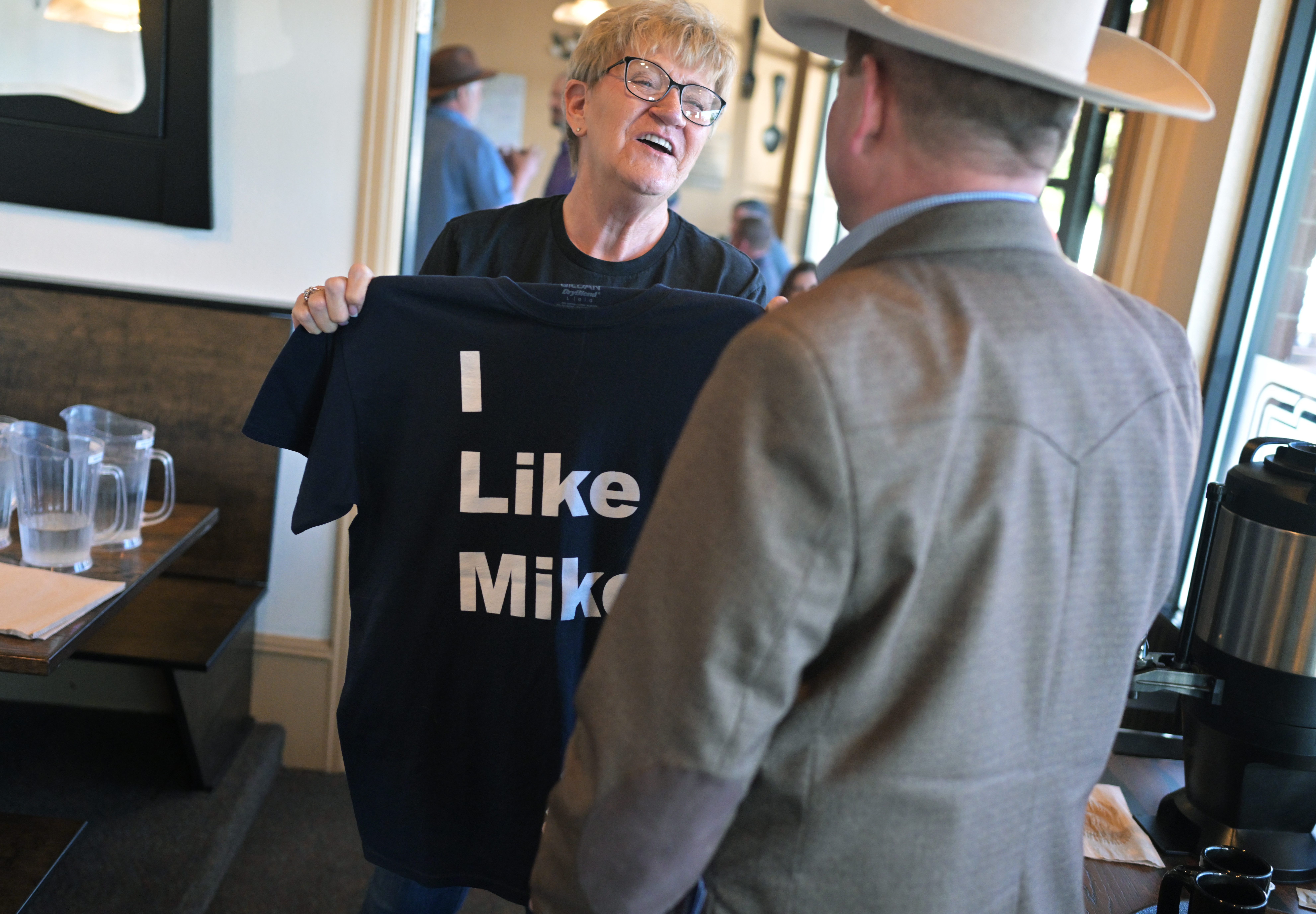 Mary Achziger, left, holds up a T-shirt she made in support of state Rep. Mike Lynch, right, as he arrives to speak with a group of Weld County GOP members during a breakfast event at Epic Egg Restaurant in Greeley on June 5, 2024. Lynch spoke with the group about why he is running in the 4th Congressional District primary race. (Photo by RJ Sangosti/The Denver Post)