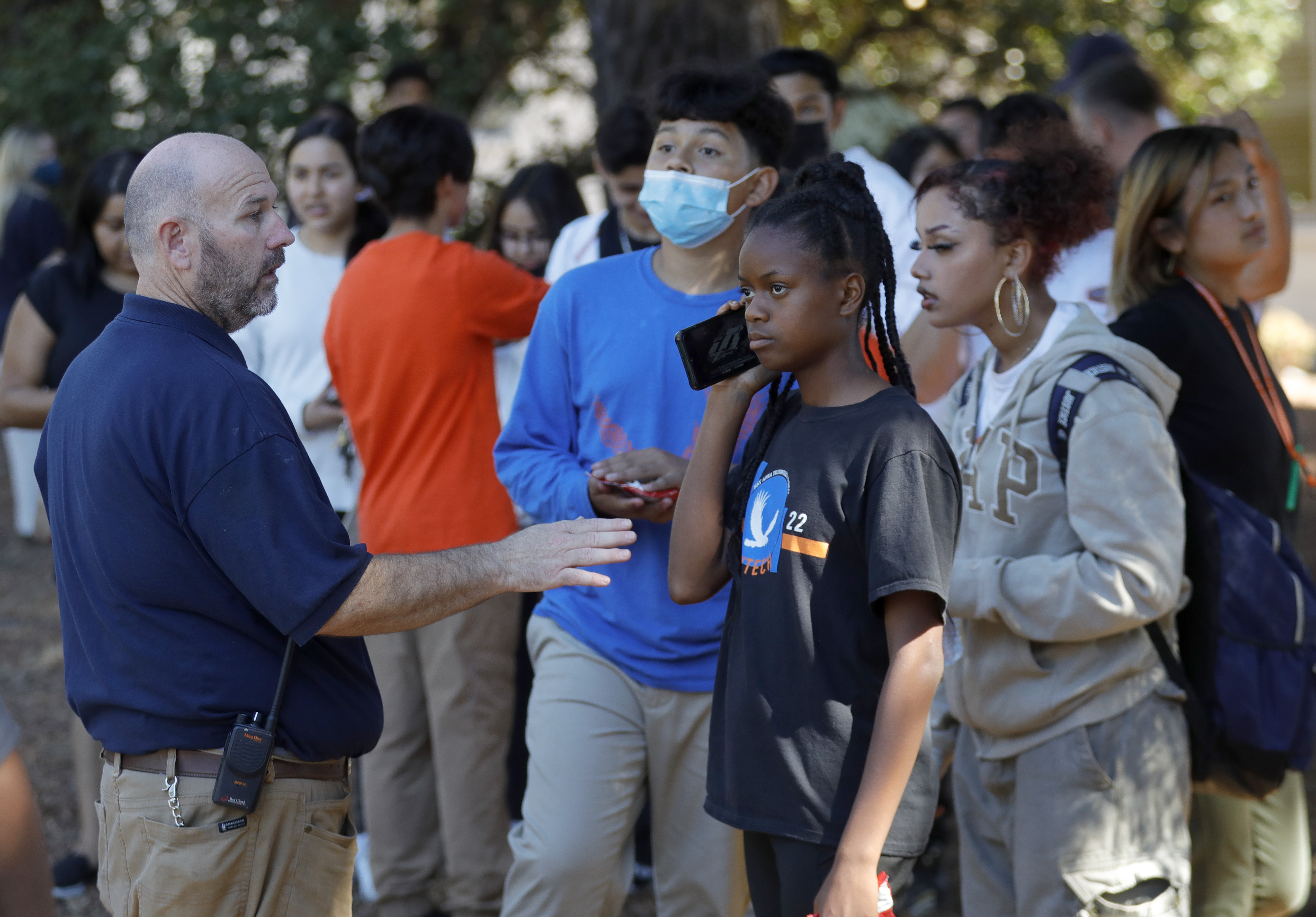 OAKLAND, CALIFORNIA - SEPTEMBER 28: Administrator Ryan Hughes, left, talks with a student at St. Cuthbert's Episcopal Church on Mountain Boulevard and Keller Avenue while law enforcement officers from several agencies respond after at least six adults were shot at the Bay Area Technology School complex in East Oakland, Calif., on Wednesday, Sept. 28, 2022. (Jane Tyska/Bay Area News Group)