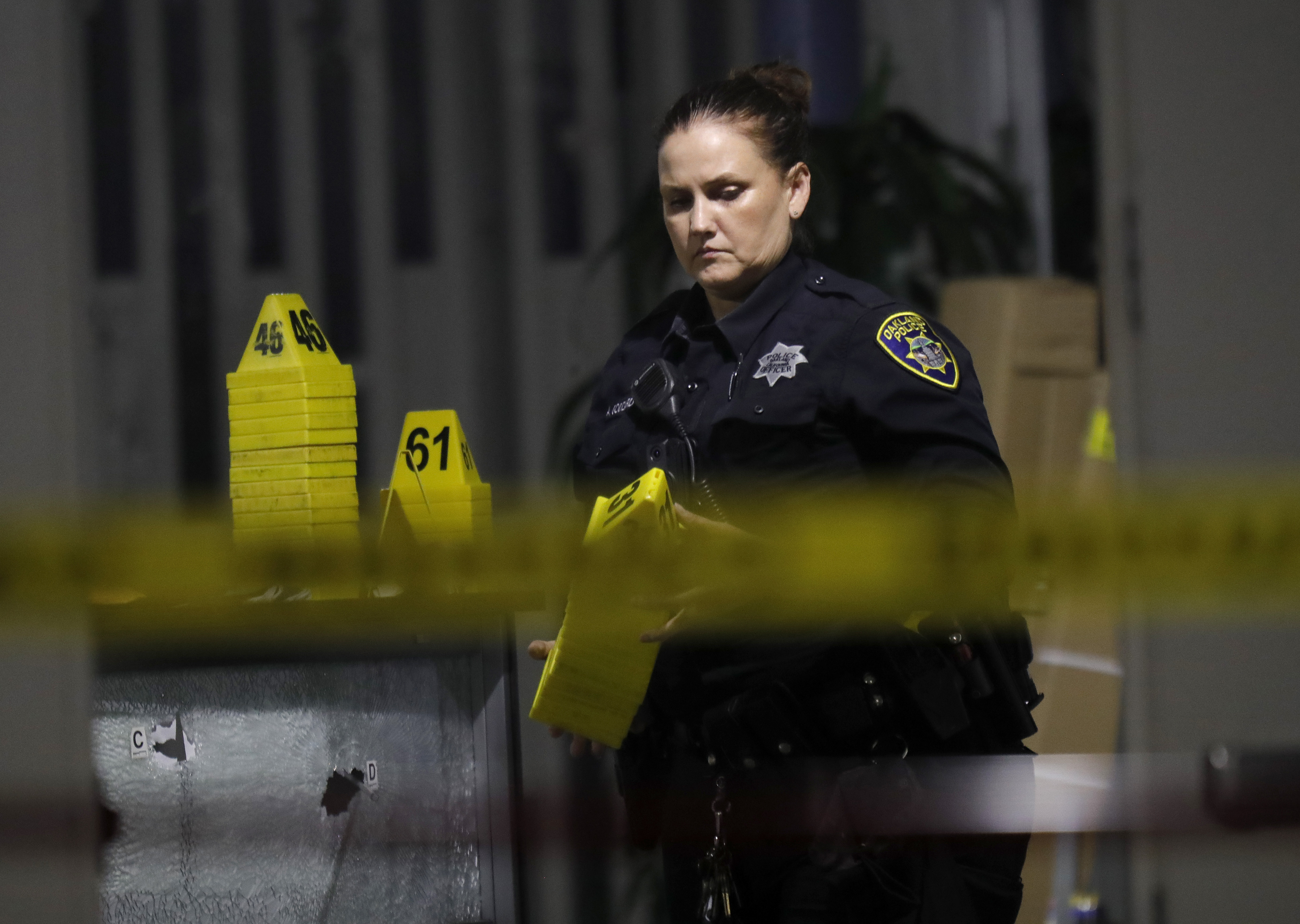 OAKLAND, CALIFORNIA - SEPTEMBER 28: An Oakland police crime scene technician gathers evidence markers as they investigate a mass shooting at the King Estates Complex school campus on Fontaine Street in East Oakland, Calif., on Wednesday, Sept. 28, 2022. Six adult victims were transported to local hospitals and two remain in critical condition. (Jane Tyska/Bay Area News Group)