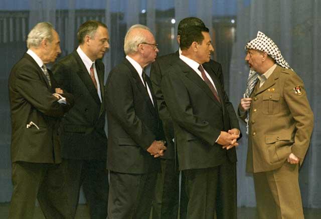 PLO Chairman Yasser Arafat stands apart as (from L to R) Israeli Foreign Minister Shimon Perez, Russian Foreign Minister Andre Kozyrev, Israeli Prime Minister Yitzhak Rabin and Egyptian President Hosni Mubarak try and persuade Arafat to sign the Cairo document after a dispute broke out over the map marking the boundaries of Jericho. 4th of May, 1994. Ph. Norbert Schiller