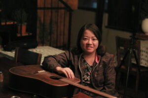 Pham Doan Trang is shown in portrait with a guitar.