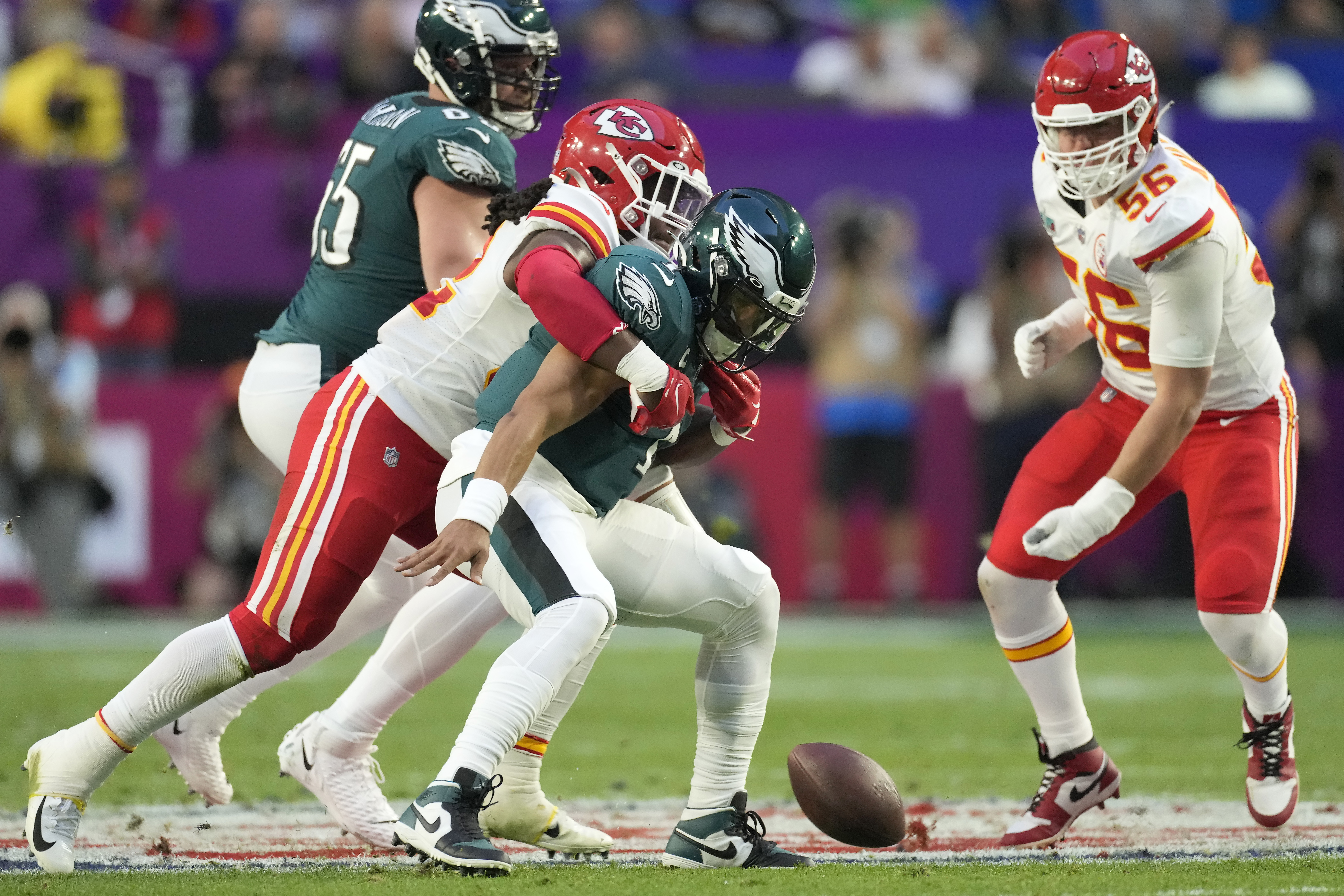 Philadelphia Eagles quarterback Jalen Hurts, middle, fumbles when hit by Kansas City Chiefs linebacker Nick Bolton during the first half of the NFL Super Bowl 57 football game between the Kansas City Chiefs and the Philadelphia Eagles, Sunday, Feb. 12, 2023, in Glendale, Ariz. Bolton ran the ball into the end zone for a touchdown. (AP Photo/Marcio J. Sanchez)
