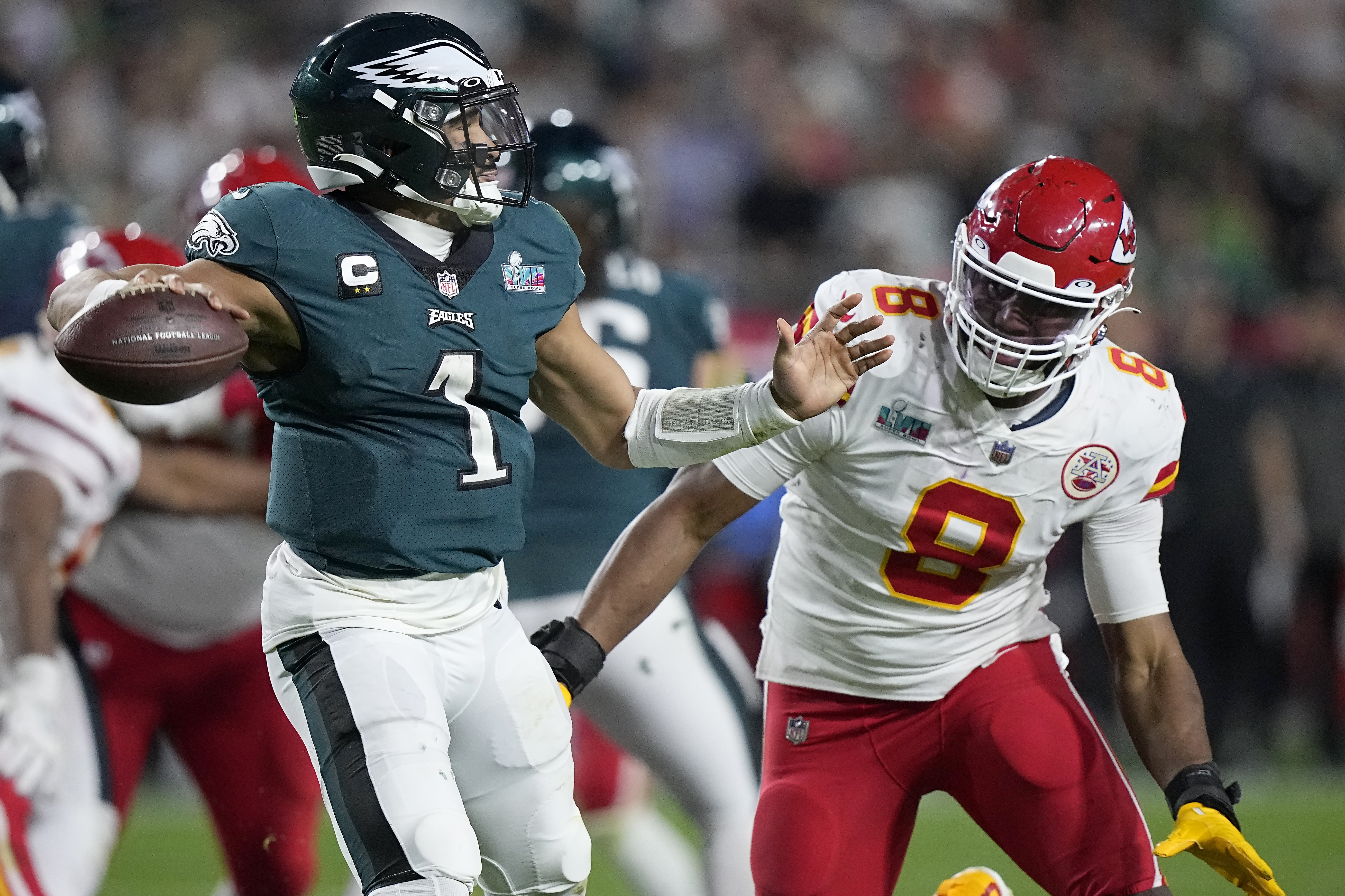 Philadelphia Eagles quarterback Jalen Hurts (1) passes under pressure by Kansas City Chiefs defensive end Carlos Dunlap (8) during the second half of the NFL Super Bowl 57 football game, Sunday, Feb. 12, 2023, in Glendale, Ariz. (AP Photo/Brynn Anderson)
