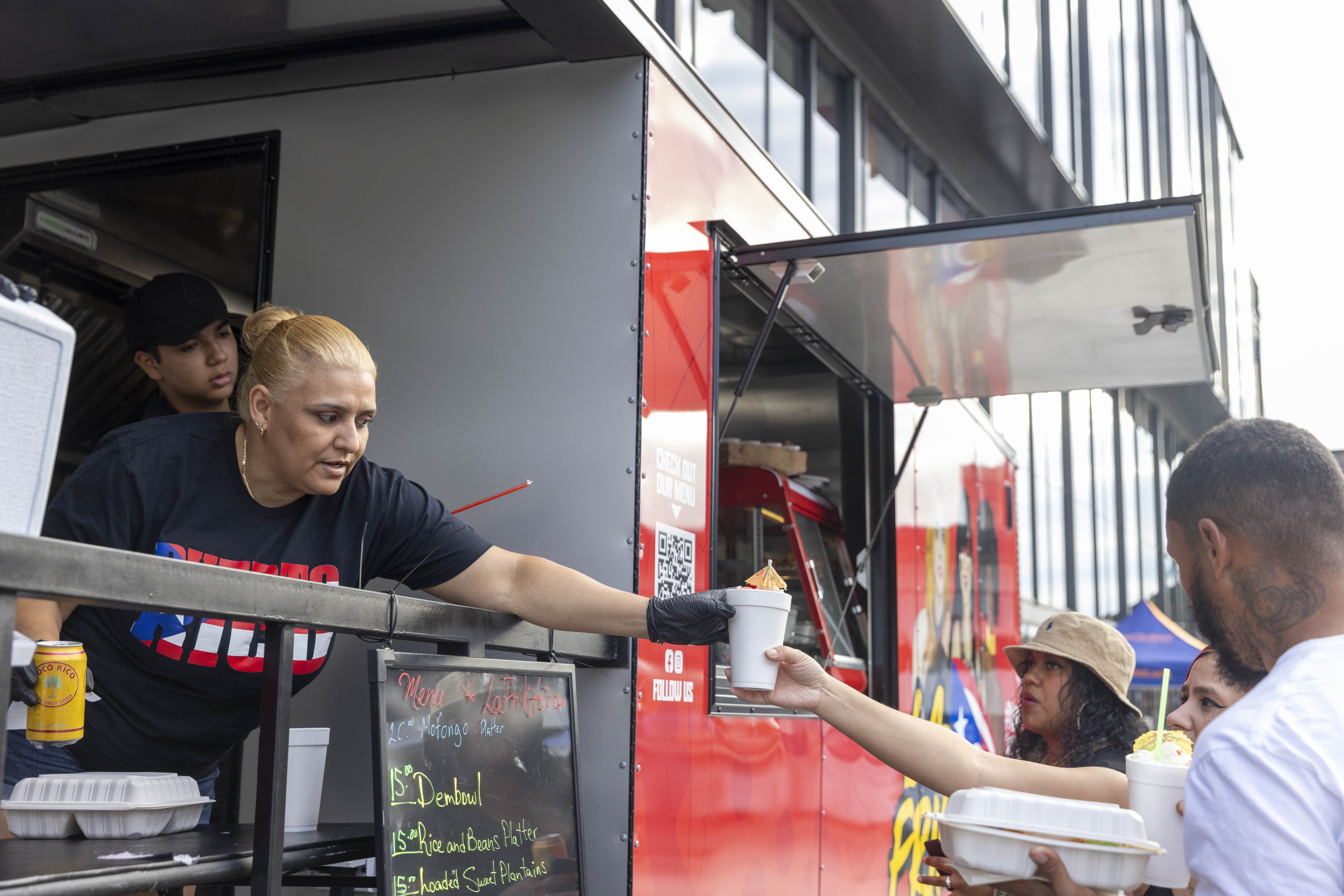 A vendor hands food to a customer Friday, June 28, 2024, during the 13th annual ¡Sabor! Latin Festival at SteelStacks in Bethlehem. The festival is a celebration of Latin heritage including music, food and family fun. (Emma Reed/The Morning Call)