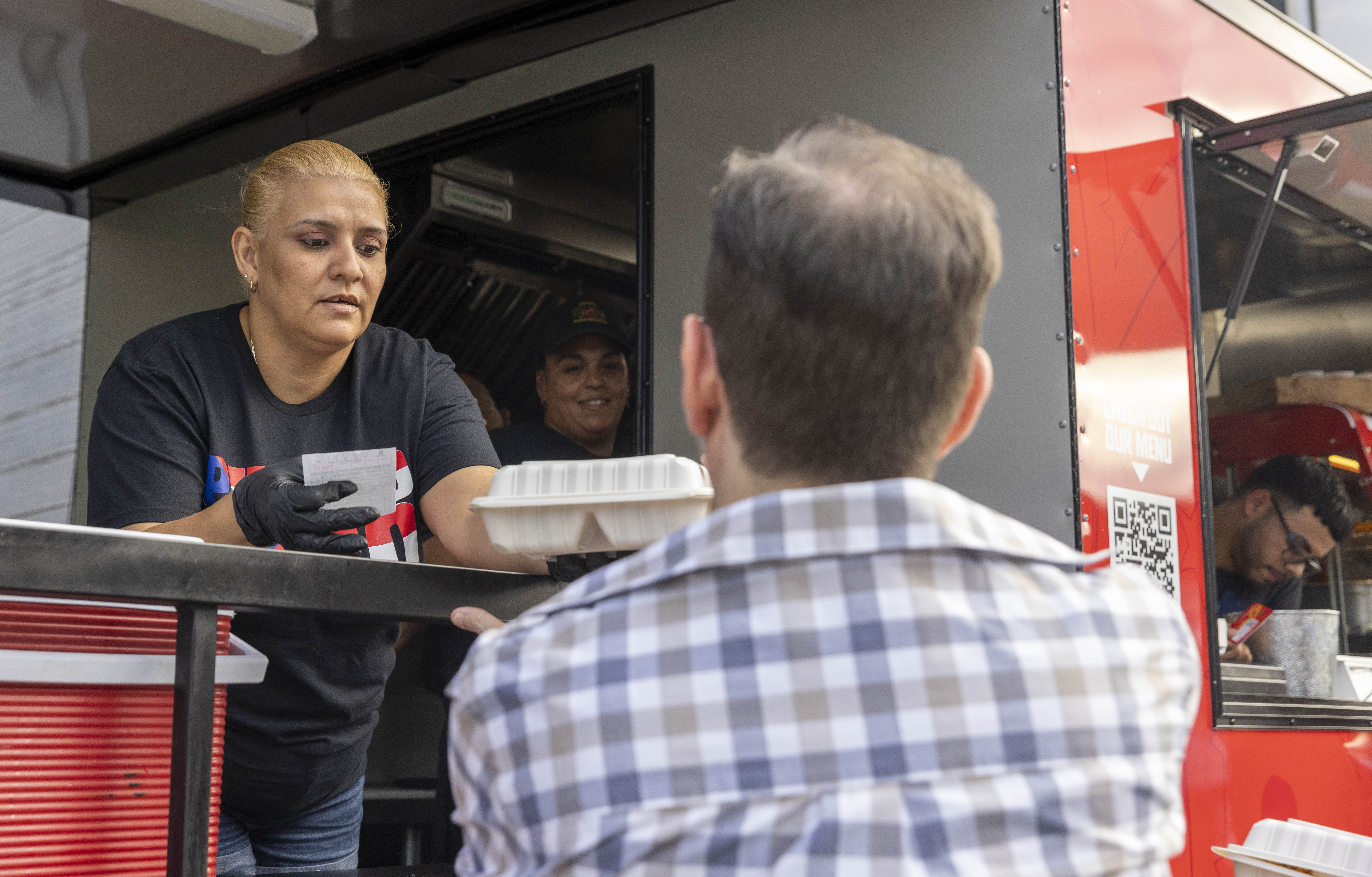 A vendor hands food to a customer Friday, June 28, 2024, during the 13th annual ¡Sabor! Latin Festival at SteelStacks in Bethlehem. The festival is a celebration of Latin heritage including music, food and family fun. (Emma Reed/The Morning Call)