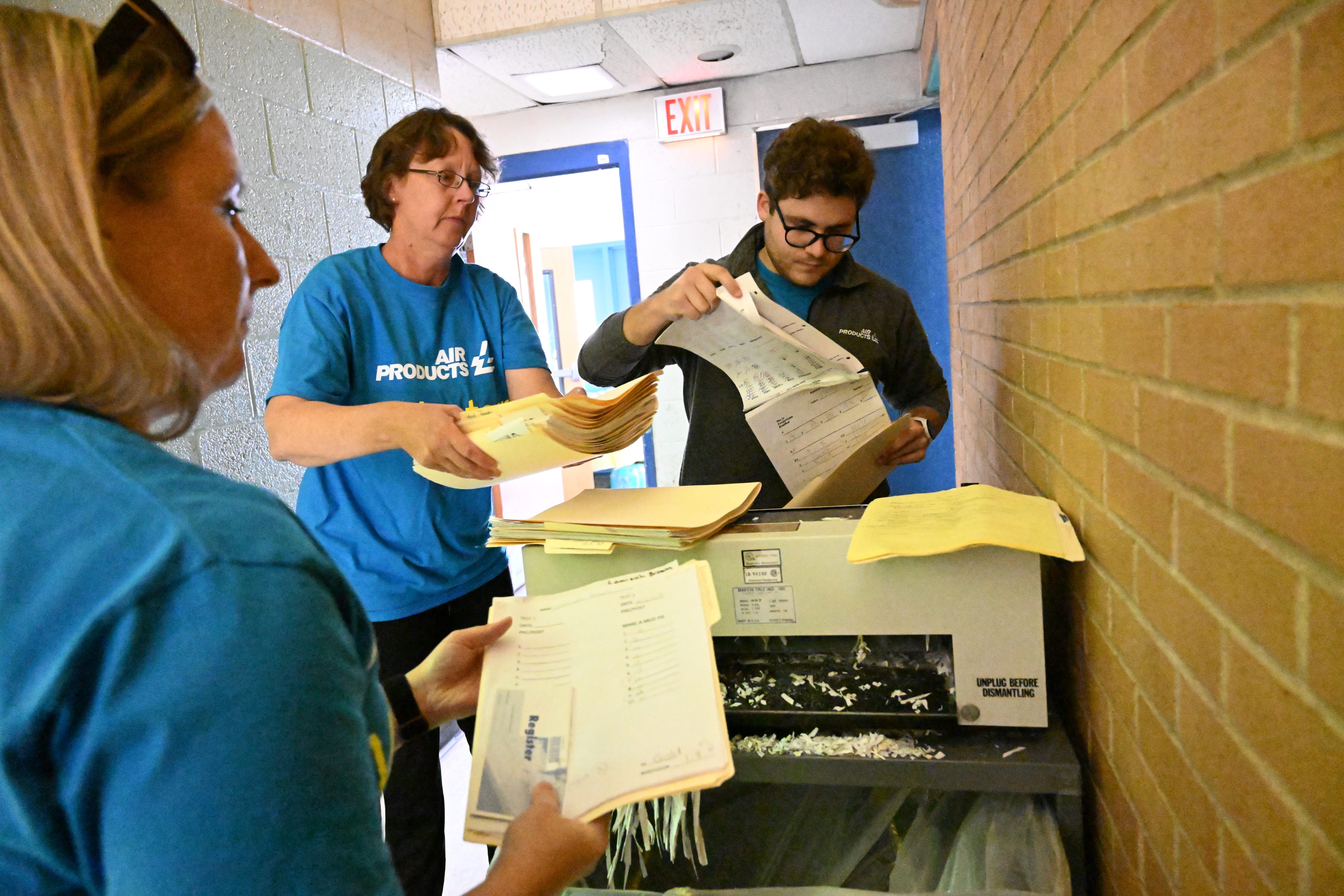 Air Products employees Lioba Kloppenburg, left, Katie Bansner, rear left, and Andrew Dinka shred documents Thursday, Sept. 19, 2024, at the Boys & Girls Club of Allentown during the United Way of the Greater Lehigh Valley's 31st annual Day of Caring. Approximately 2,300 volunteers from 54 area businesses completed community service projects at dozens of nonprofits throughout Lehigh and Northampton counties. (Amy Shortell/The Morning Call)