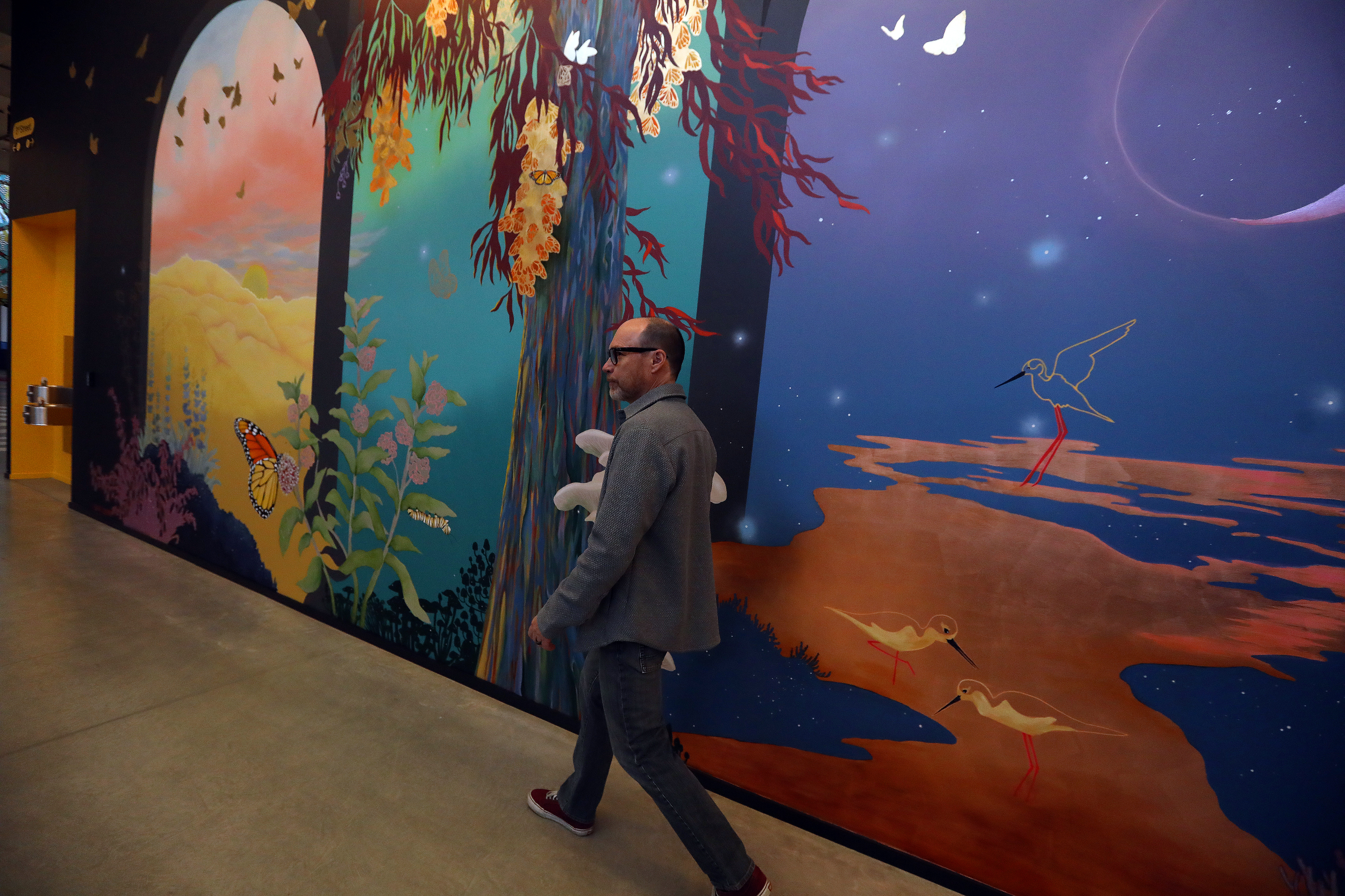 David Radcliffe, Vice President, Real Estate and Workplace Services at Google walks past a mural in the new Bay View campus