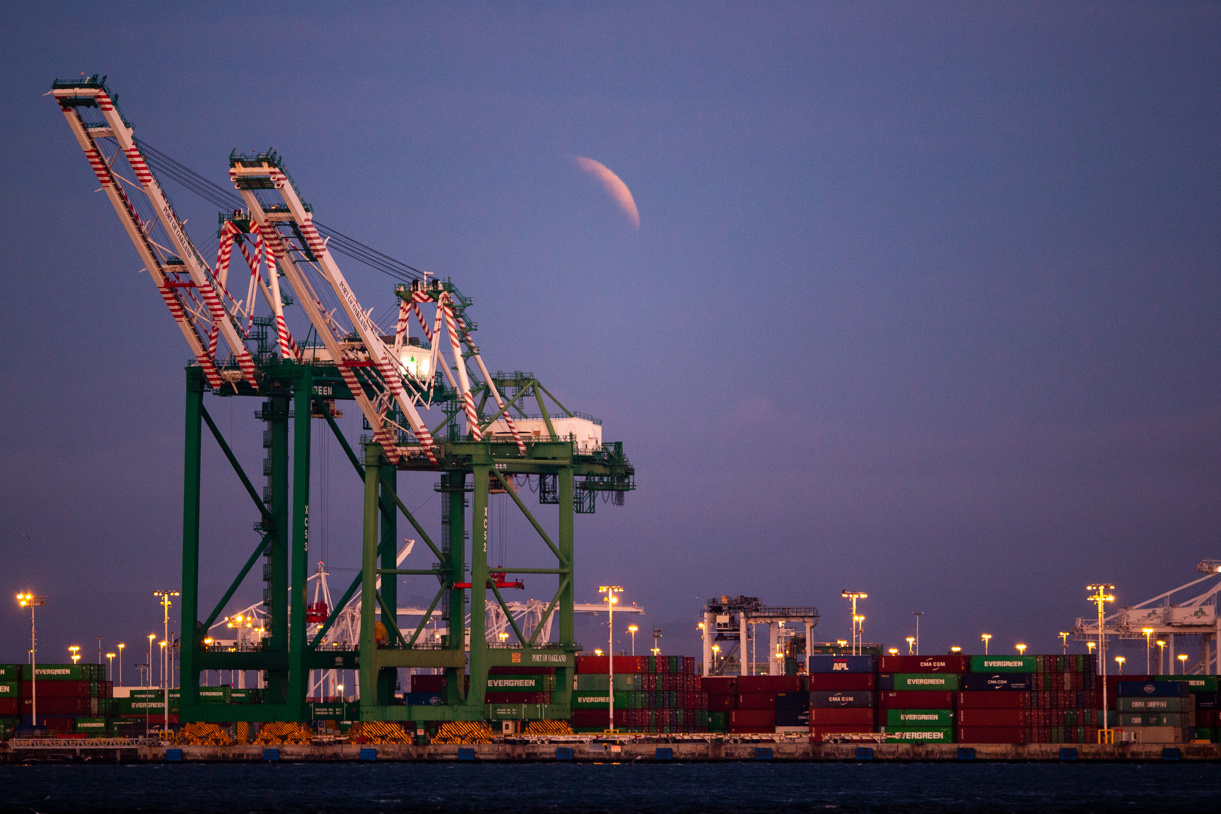 The blood moon lunar eclipse rises behind the Port of Oakland.