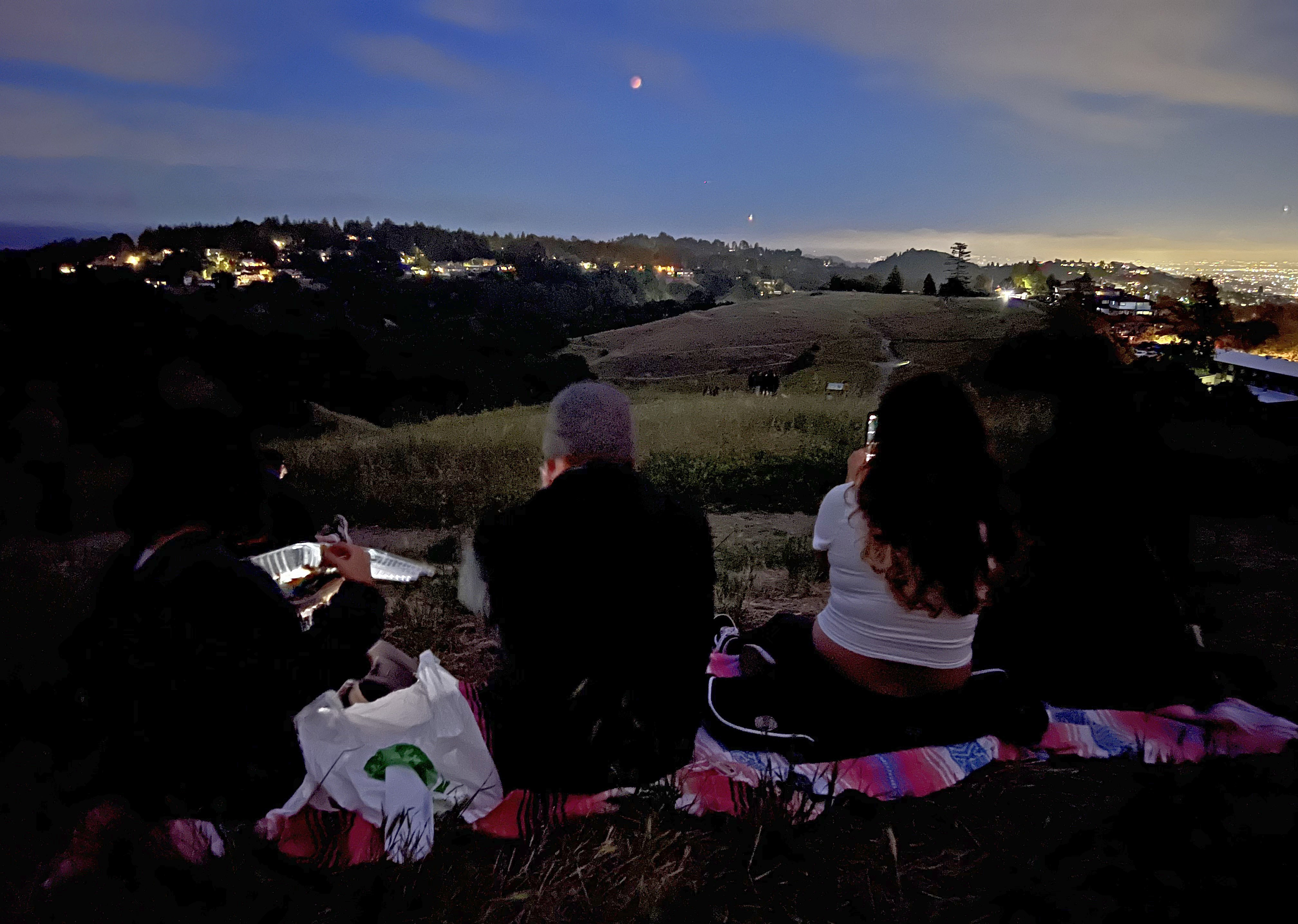 People gather to view a lunar eclipse of the first blood moon of the year in Oakland, Calif.