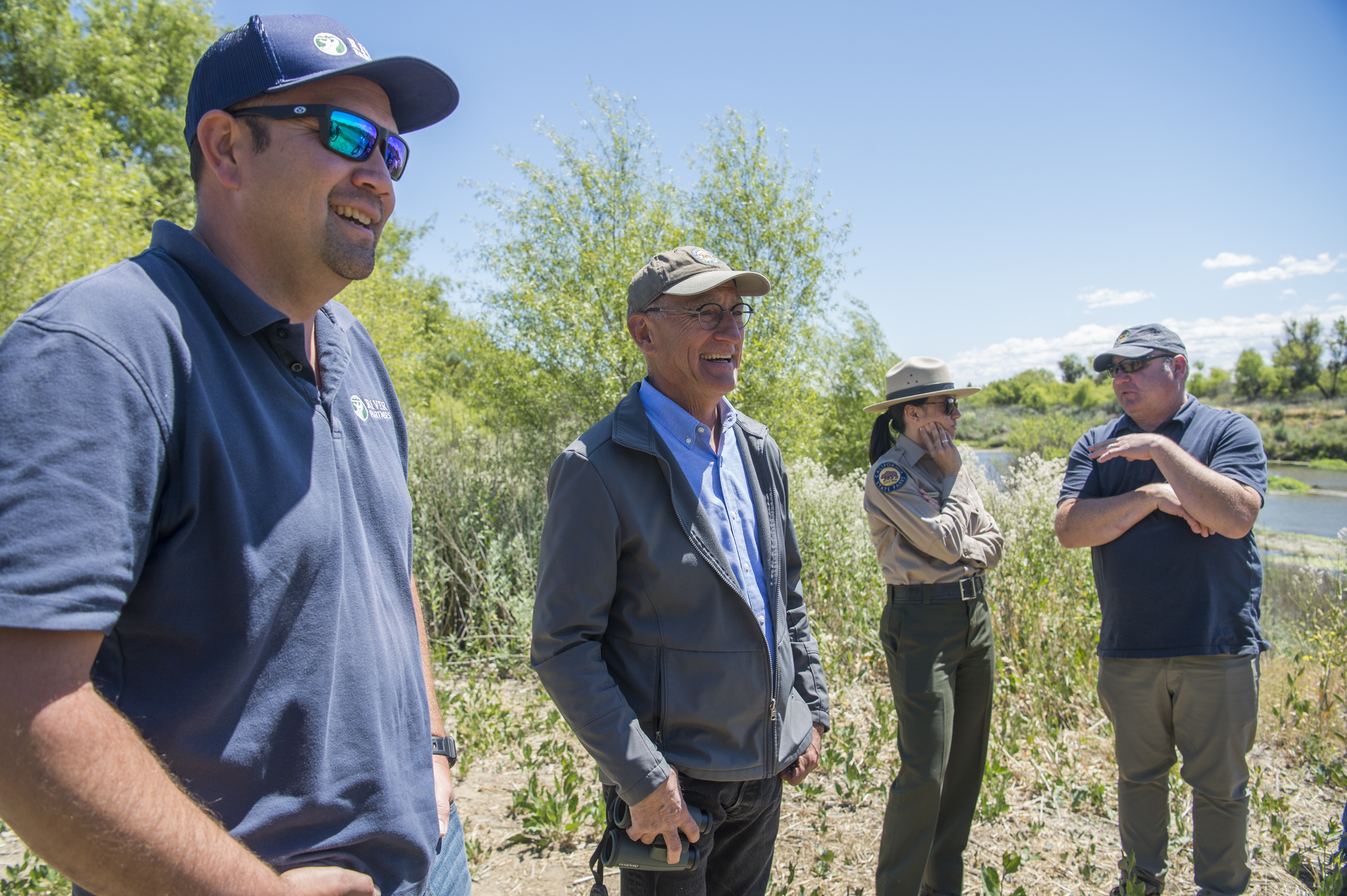 From left, Austin Stevenot, San Joaquin Valley field manager for River Partners, and Armando Quintero, director for the California Department of Parks and Recreation, stand next to Daniel Gerhart, superintendent of the California State Parks Central Valley District, and Brian Dewey, Assistant Deputy Director/Acquisitions and Development for the California Department of Parks and Recreation, as they talk while looking at the view of the San Joaquin River at a new park location in Modesto, Calif.