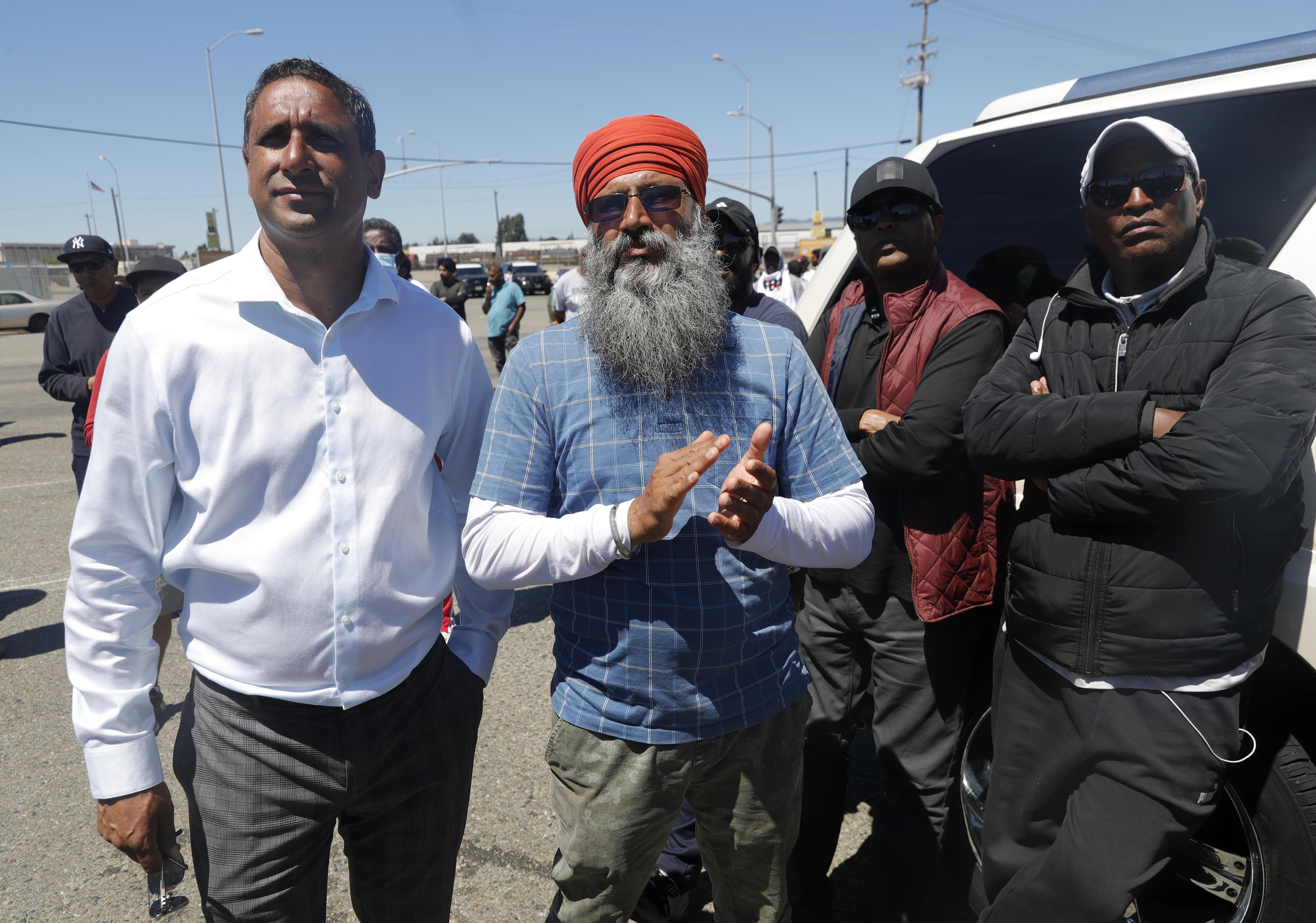 OAKLAND, CALIFORNIA - JULY 21: Spokesperson Navdeep Gill and truck driver Kulginder Singh, from left, take part in a truckers rally during a protest in front of Matson shipping at the Port of Oakland in Oakland, Calif., on Thursday, July 21, 2022. Truck drivers have blocked access to container terminals in protest of state Assembly Bill 5, a bill that creates standards for classifying workers as independent contractors. (Jane Tyska/Bay Area News Group)