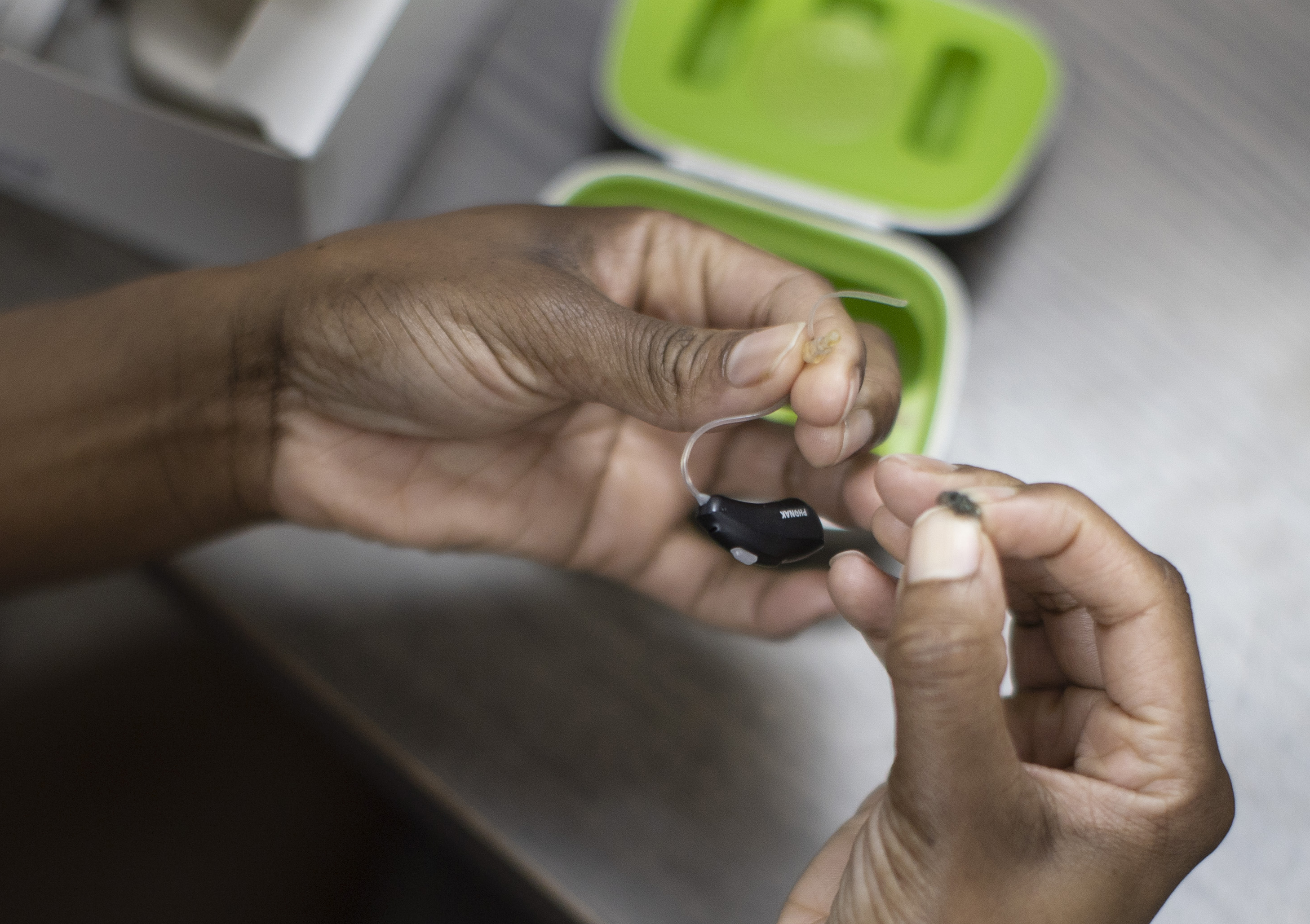A patient holds her hearing aid as she visits Hear Again America for a checkup on October 20, 2021 in Fort Lauderdale, Florida. The Food and Drug Administration announced that people with mild or moderate hearing loss could soon buy hearing aids without a medical exam or special fitting. (Photo by Joe Raedle/Getty Images)