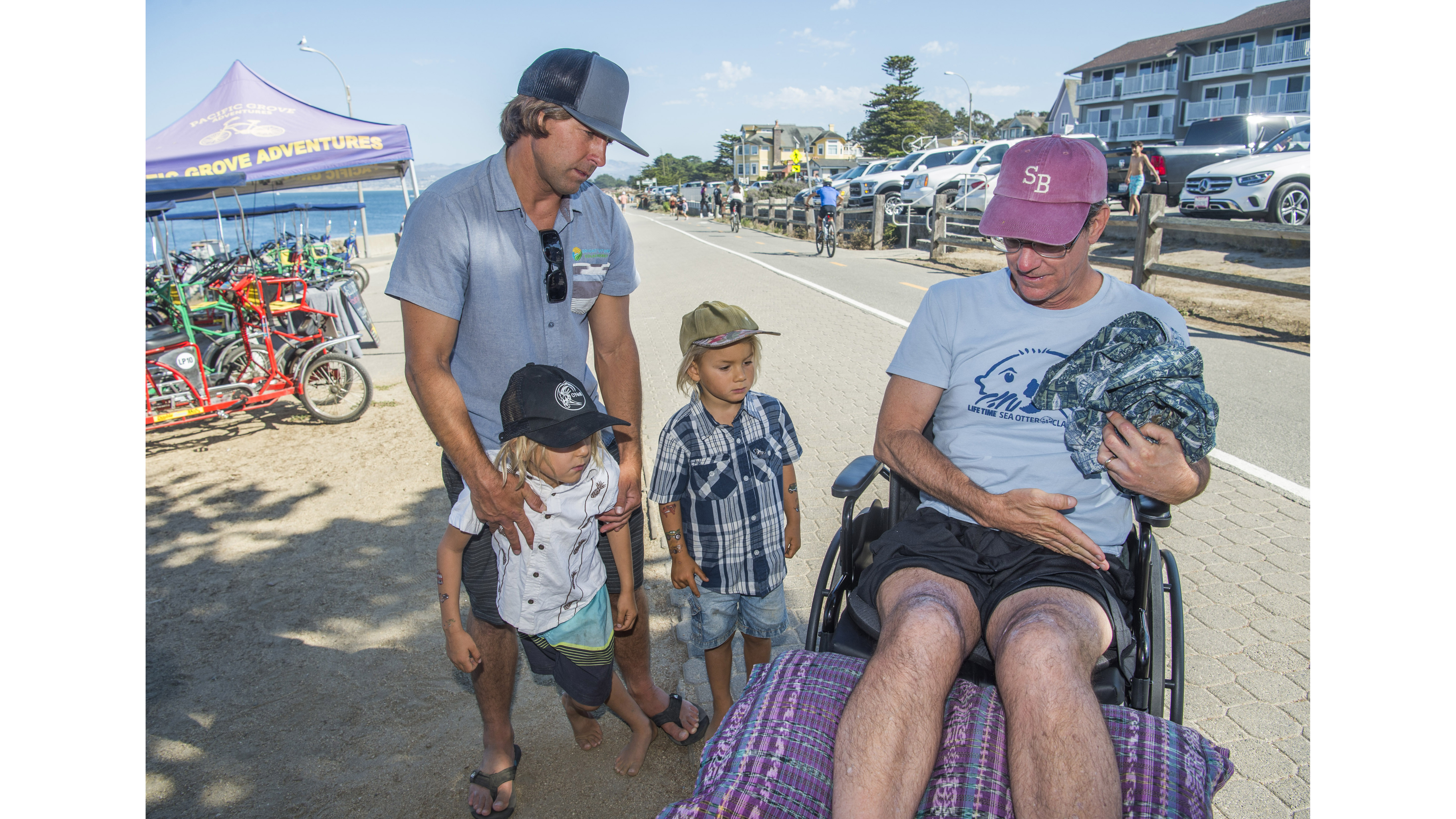 Heath Braddock, of Elkhorn, and his two sons Asher 6, left, and Noah, 4, is shown the shark bite scars Steve Bruemmer received after an attack at Lovers Point in Pacific Grove, Calif., on Monday, Sept. 5, 2022. Braddock, along with Aimee Johns and Paul Bandy, are credited with saving Bruemmer after getting him out of the water after he was bitten by a large great white shark while swimming on June 22, 2022, at Lovers Point. Bruemmer is a member of the Kelp Krawlers, a group of open-water swimmers and triathletes who swim at Lovers Point and other locations. (Doug Duran/Bay Area News Group)