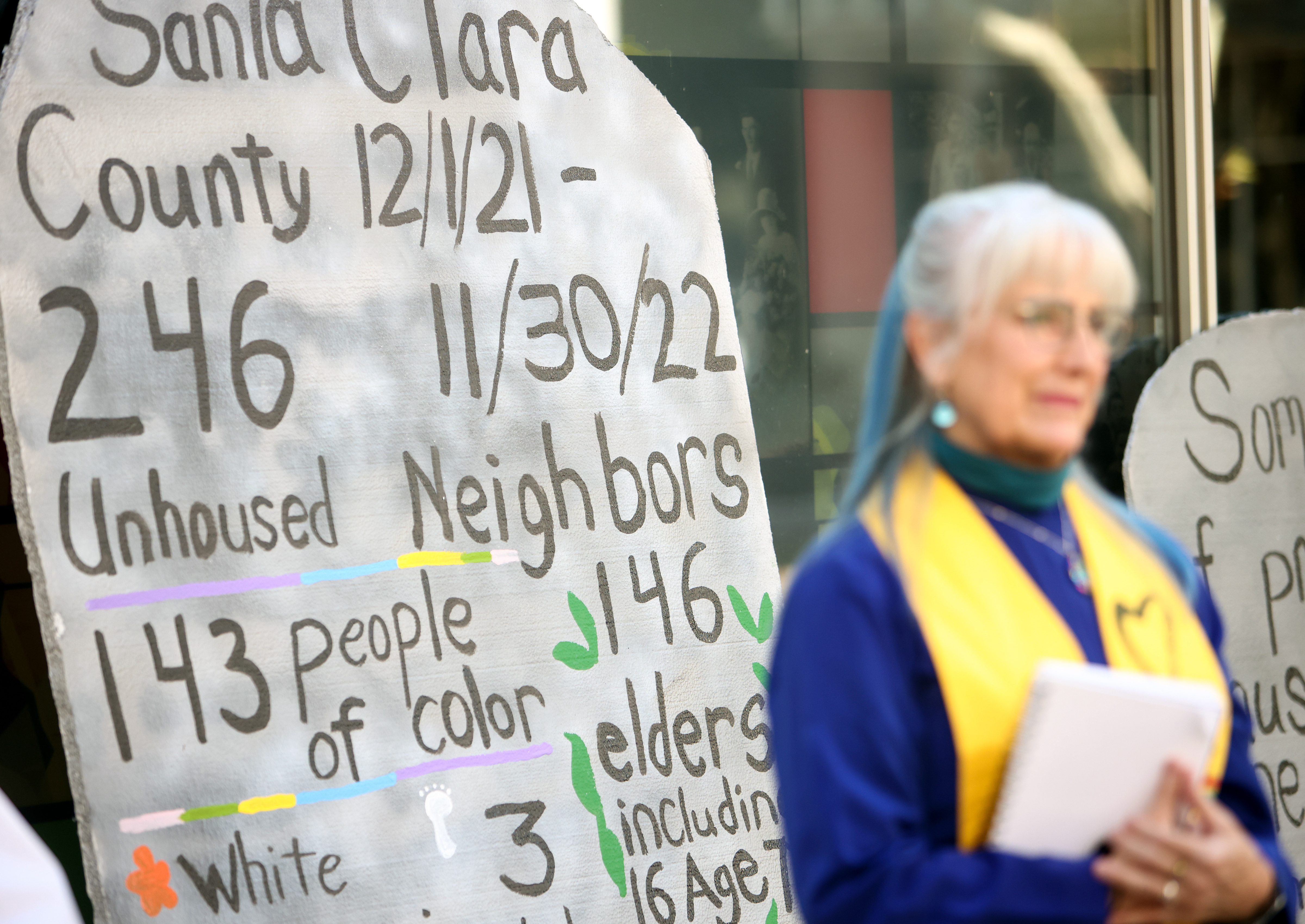 Reverend Nancy Palmer Jones, senior minister of the First Unitarian Church in San Jose, stands in front a tombstone during an annual memorial for all unhoused people who died over the past year at the Santa Clara County building in San Jose, Calif., on Wednesday, Dec. 21, 2022. (Shae Hammond/Bay Area News Group)