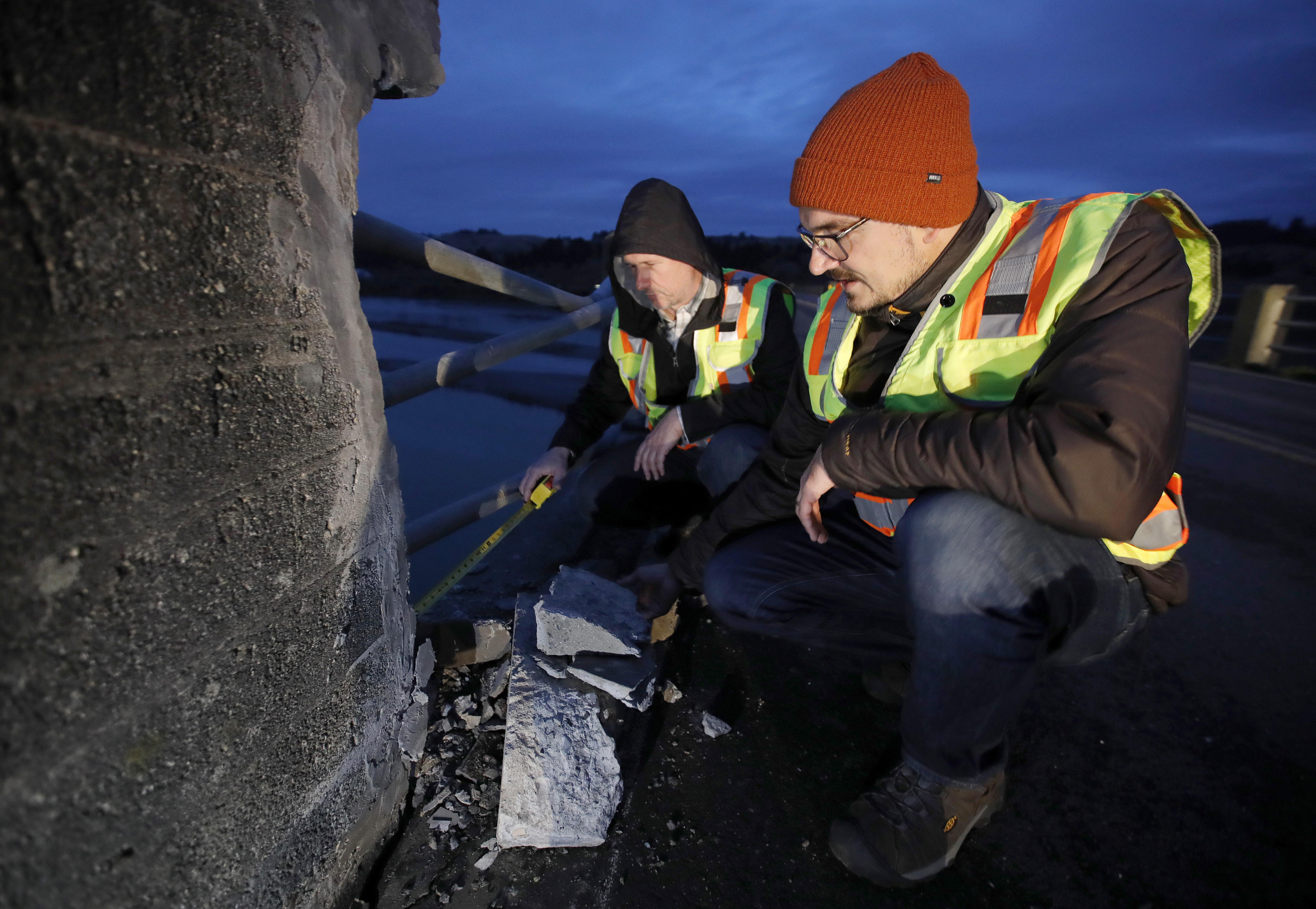 Vladimir Calugaru and Nikolai Dumbrowski, of InfraTerra, from right, check structural damage to the 1911 Fernbridge just outside of Ferndale, Calif., on Tuesday, Dec. 20, 2022.
