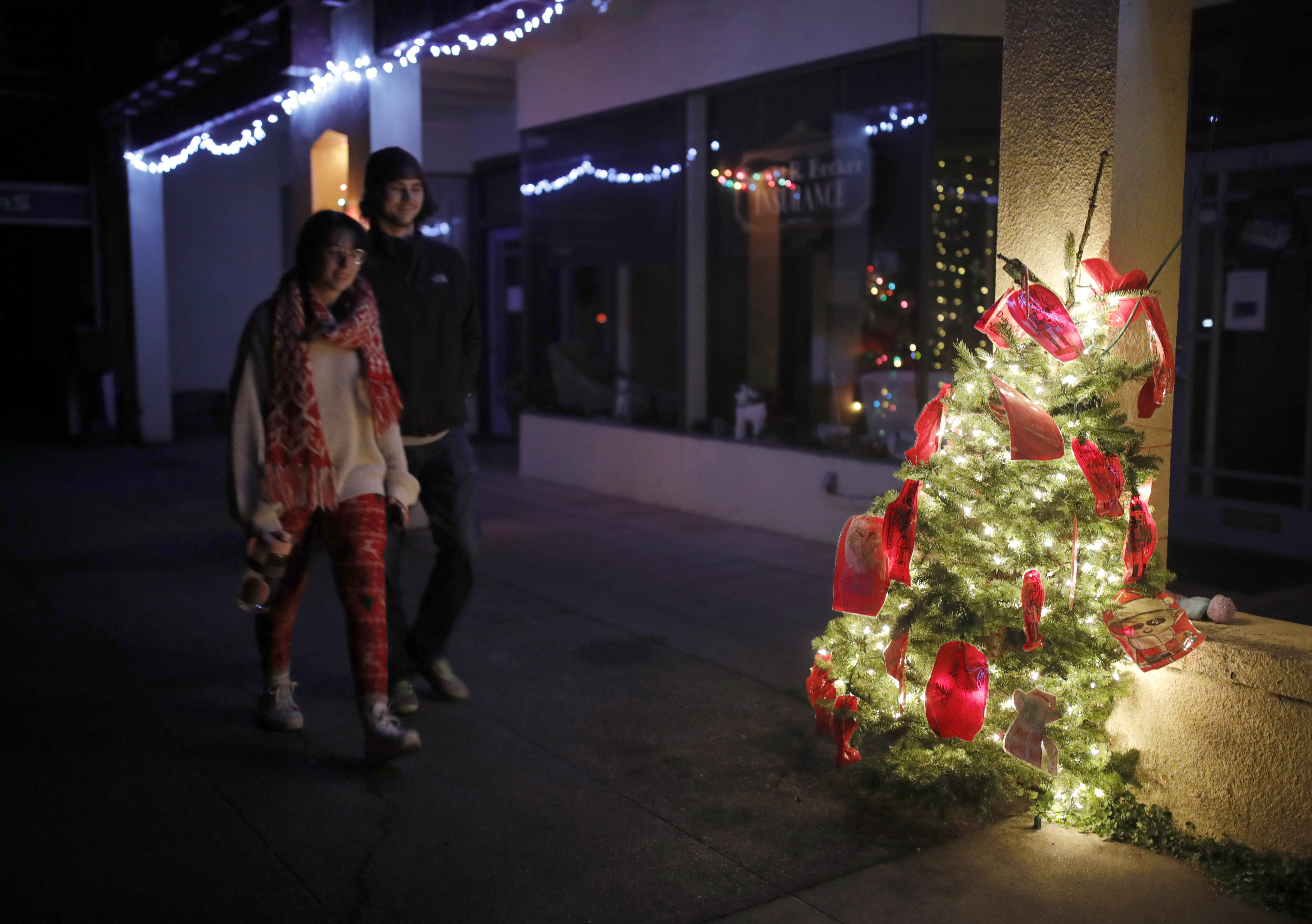 People walk down a darkened Francis Street as a solitary Christmas tree glows in Ferndale, Calif., on Tuesday, Dec. 20, 2022. Ferndale and many other communities were without power after a 6.4 magnitude earthquake struck the coastline near Eureka early Tuesday.