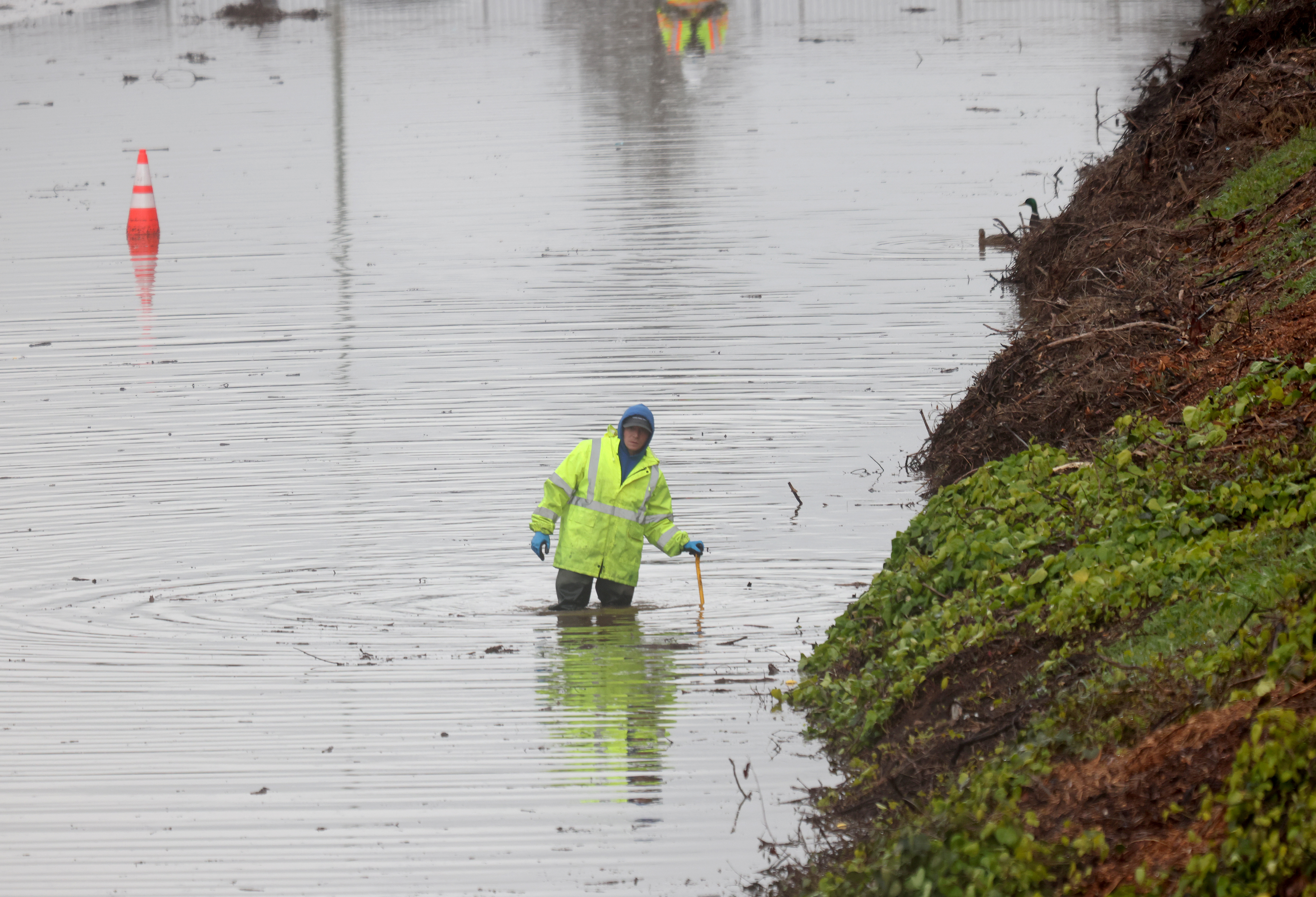 A Caltrans worker clears a storm drain on Interstate 580 eastbound in Oakland, Calif., on Friday, March 10, 2023. The freeway was closed between High Street and 35th Avenue due to flooding. 