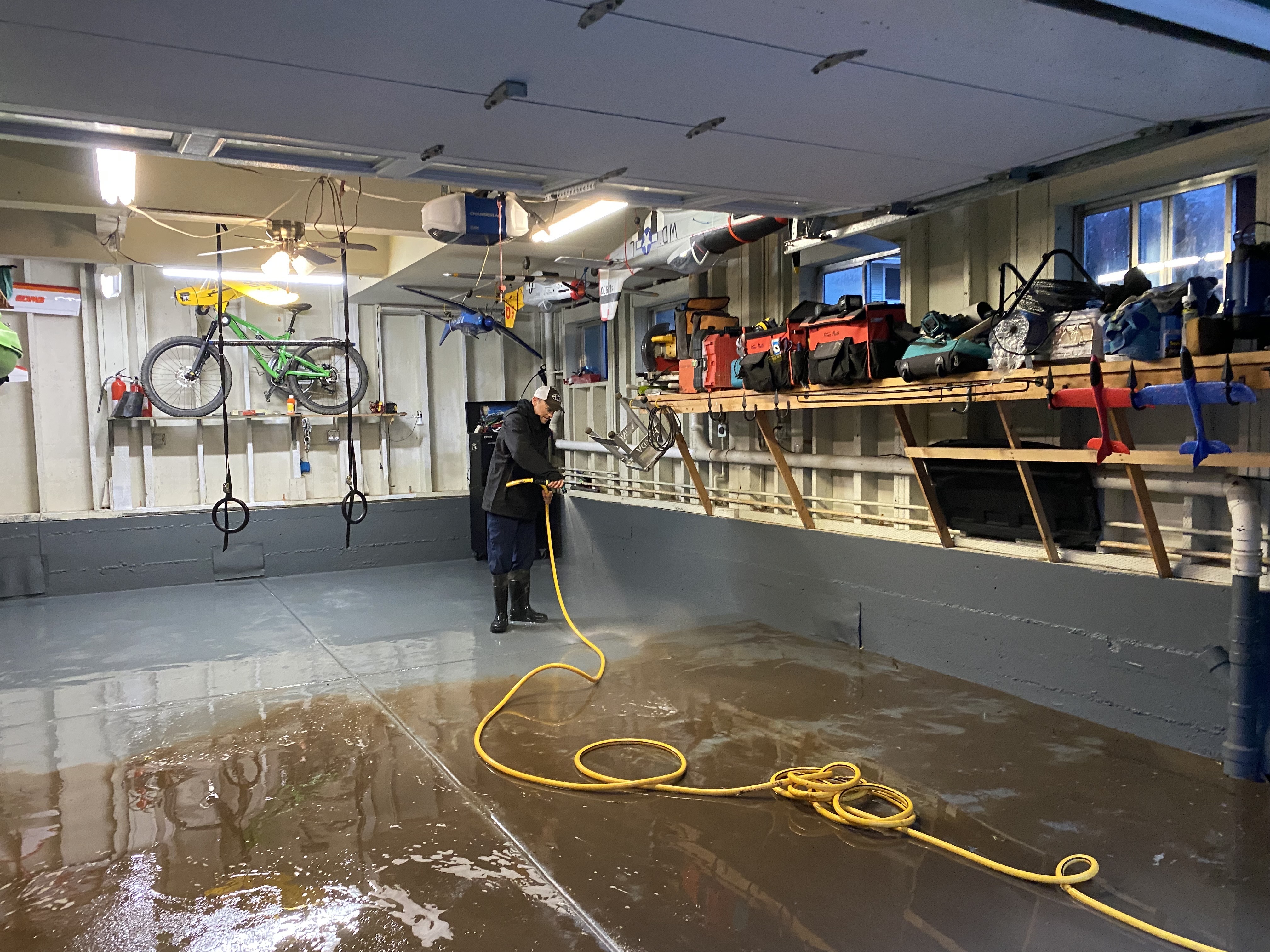Jason Dietz, 48, a 20 year resident of Felton, hoses out his garage where the nearby San Lorenzo River reached moderate flood stage March 10, 2023. It was the fourth time this winter that his home flooded. The living quarters are above the concrete garage. In the worst flood in January, floodwater topped the elevated shelves in Dietz's garage. 