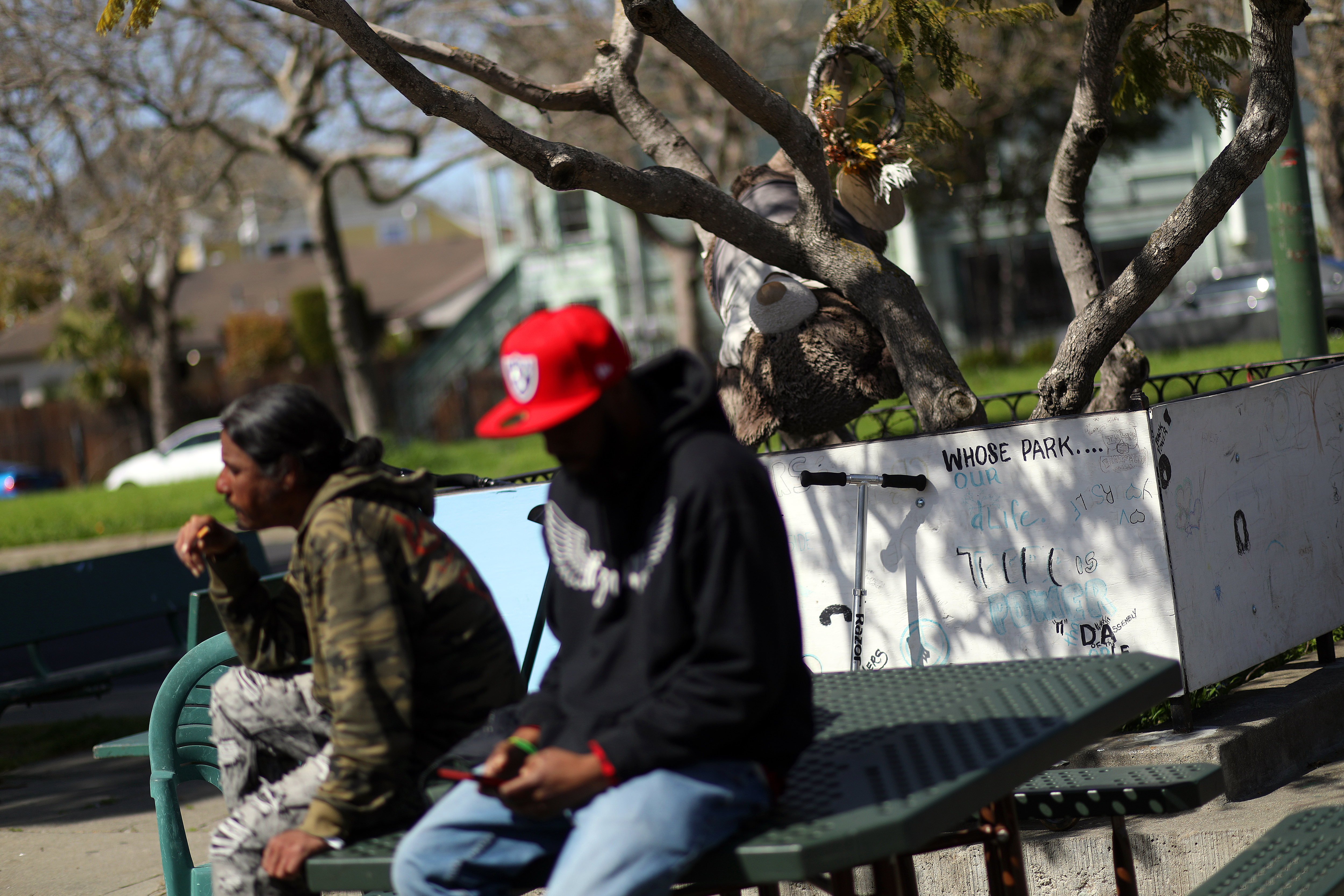 Community members sit near artwork at Driver Plaza on Wednesday, March 15, 2023, in Oakland, Calif.