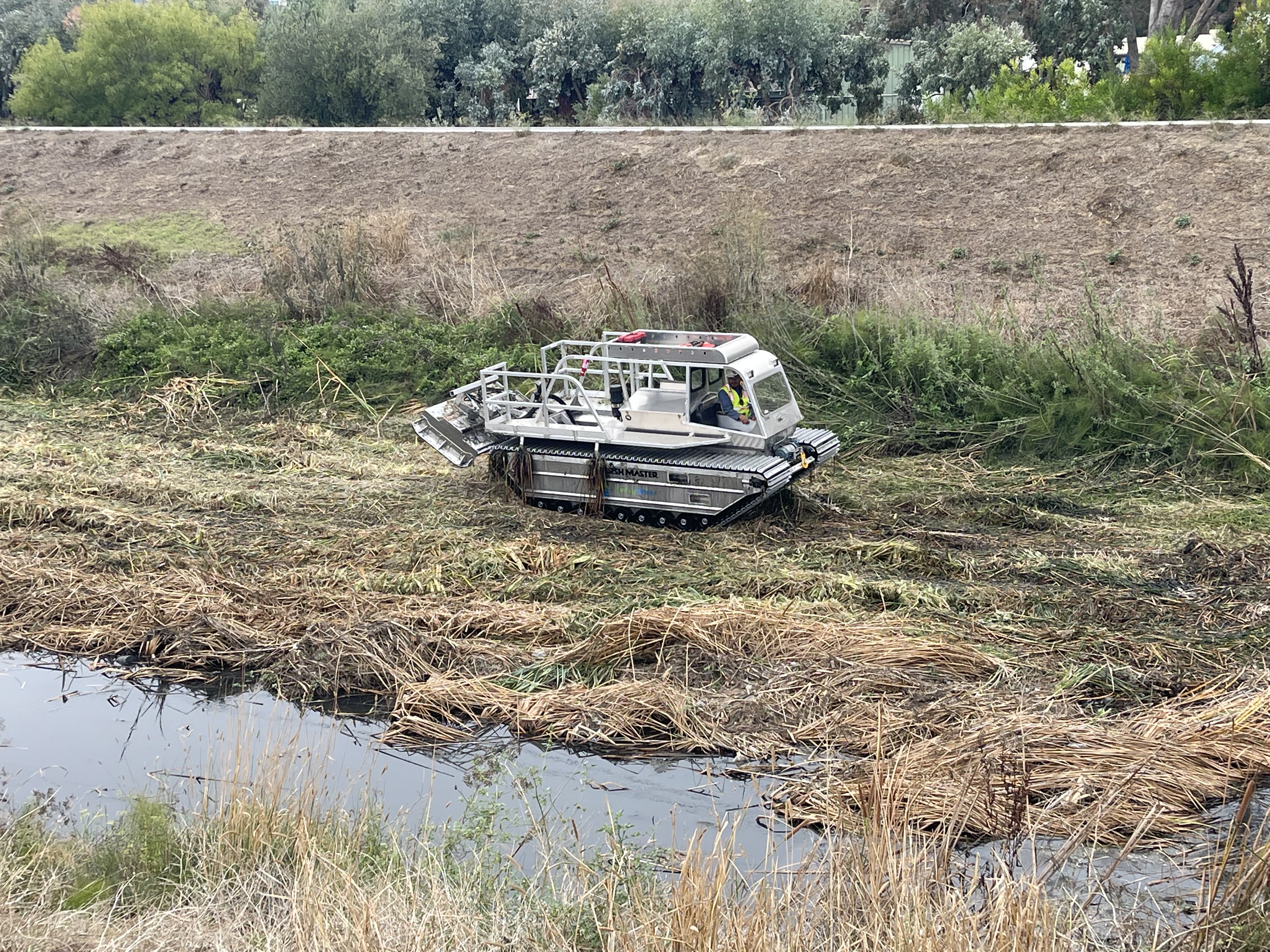 Valley Water crews use a marsh buggy to mow down tall vegetation alongside levees in preparation for winter creek flows along San Tomas Aquino Creek between Agnew Road and the Hetch Hetchy Pipeline crossing near Levi's Stadium in Santa Clara.