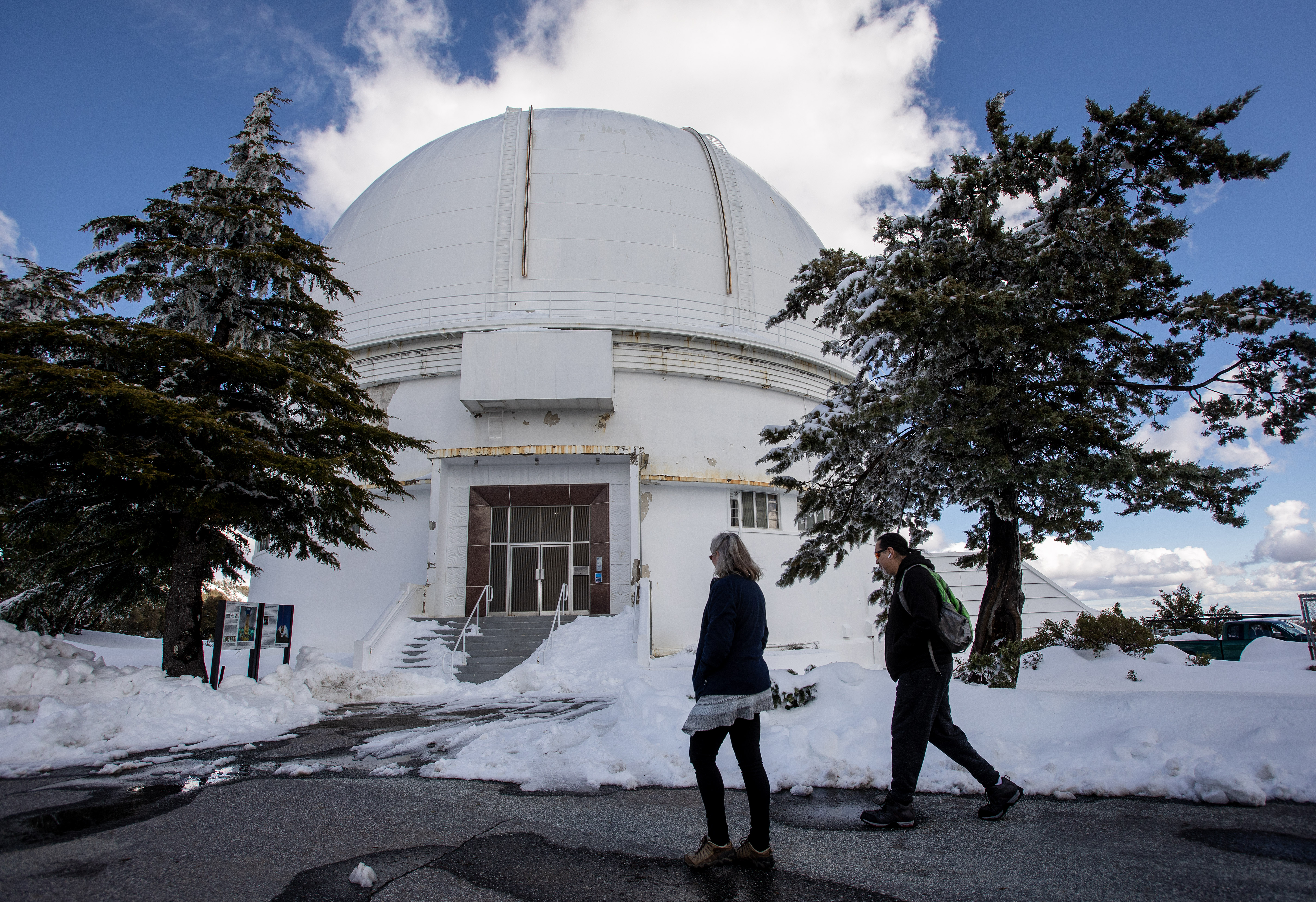 Lick Observatory resident astronomer Elinor Gates and telescope technician Shawn Stone walk past snow toward the Shane telescope atop Mount Hamilton, Tuesday, March 7, 2023.