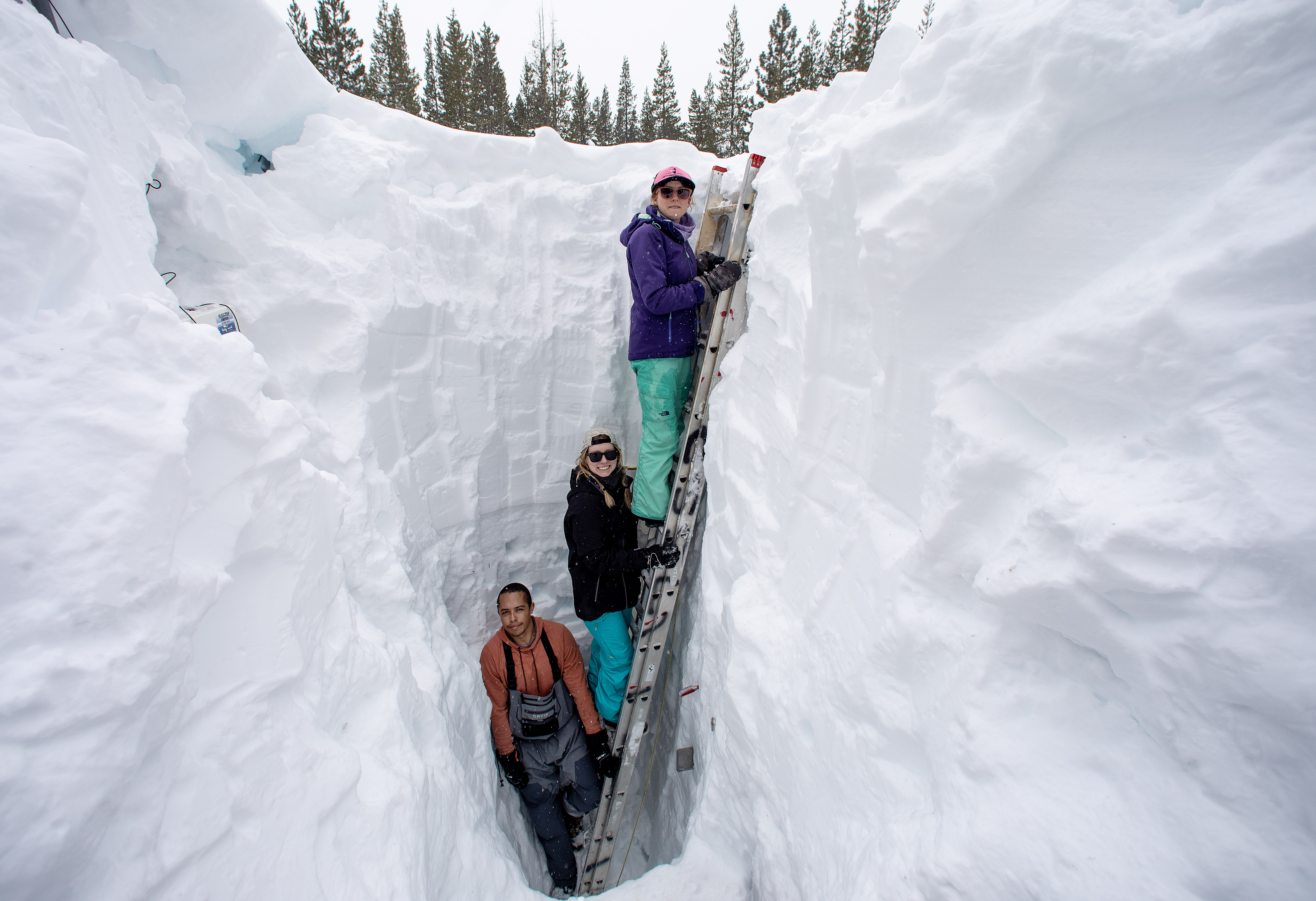 Working inside a nearly 18-foot-deep snow pit at the UC Berkeley Central Sierra Snow Lab, from left, Shaun Joseph, Claudia Norman and Helena Middleton take measurements of snow temperatures ahead of an atmospheric weather storm, Thursday, March 9, 2023, in Soda Springs, Calif.