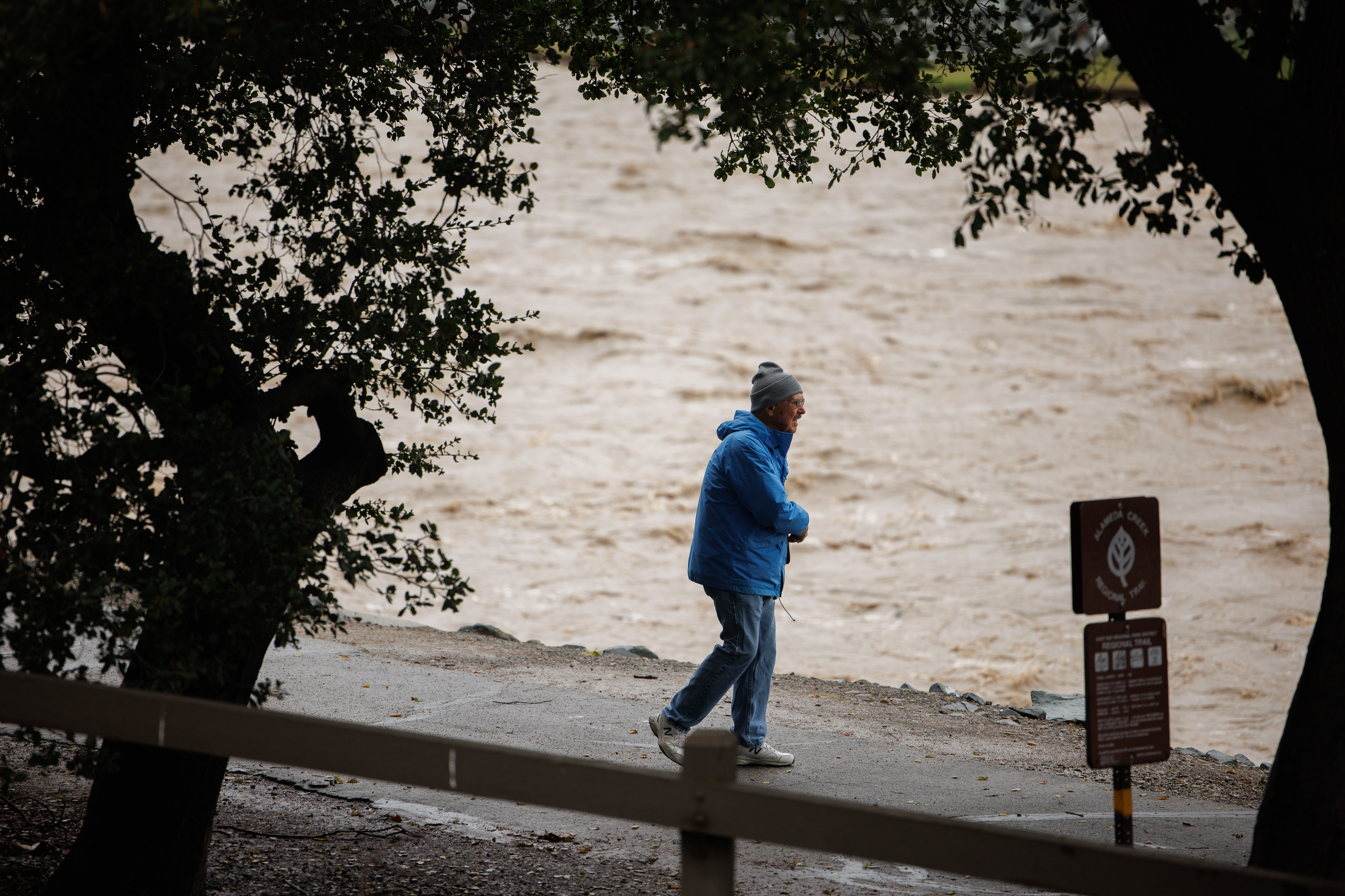 Jerry Fore of Fremont looks at the water level of Alameda Creek in Fremont, Calif., as the latest atmospheric river storm system hits the Bay Area on Friday, March 10, 2023.