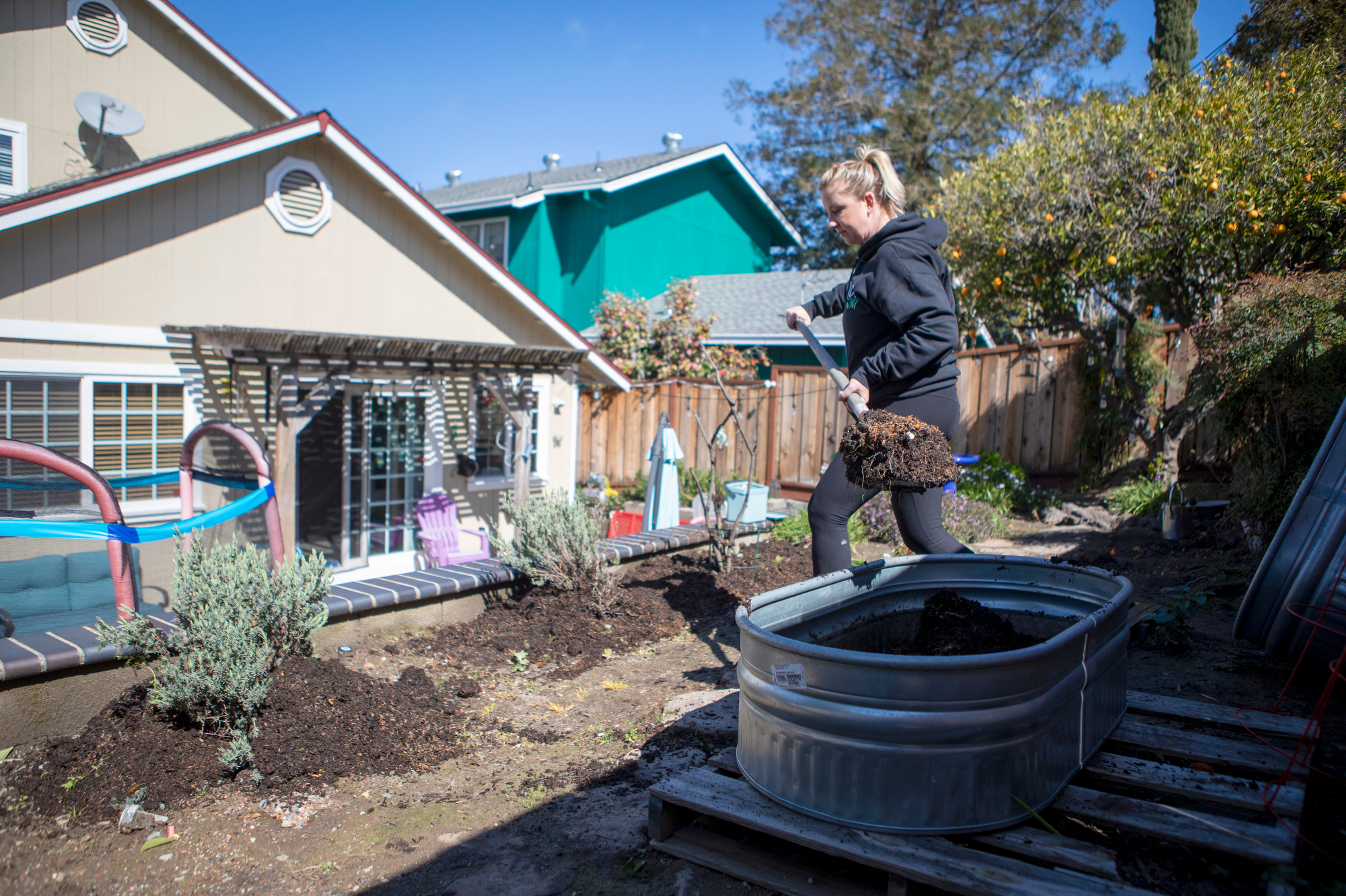 Jenna Cassel is replacing the organic soil from her backyard garden beds and spreading it out to other plants that do not produce food at her home along Shell Avenue near the Martinez Refining Company site, in Martinez, Calif., on Wednesday, March 8, 2023. The refinery accidentally released dust containing heavy metals in November and on Tuesday the Contra Costa Health Services advised people to not eat food grow in their gardens until they have tested or replaced their soil. (Anda Chu/Bay Area News Group)