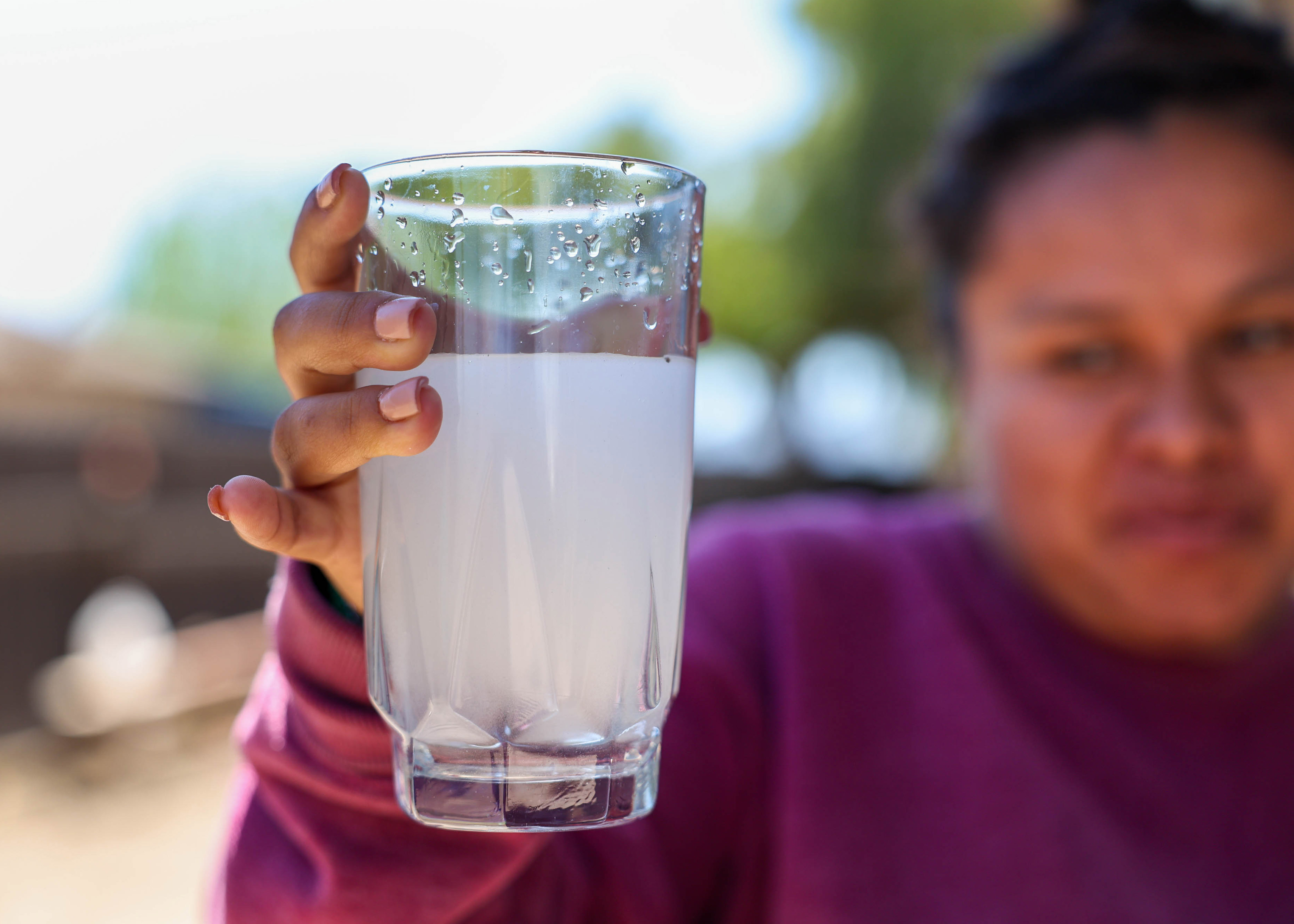 Andrea Silva holds a glass of cloudy water from the faucet at her home in San Lucas, Calif., on Thursday, April 14, 2023.