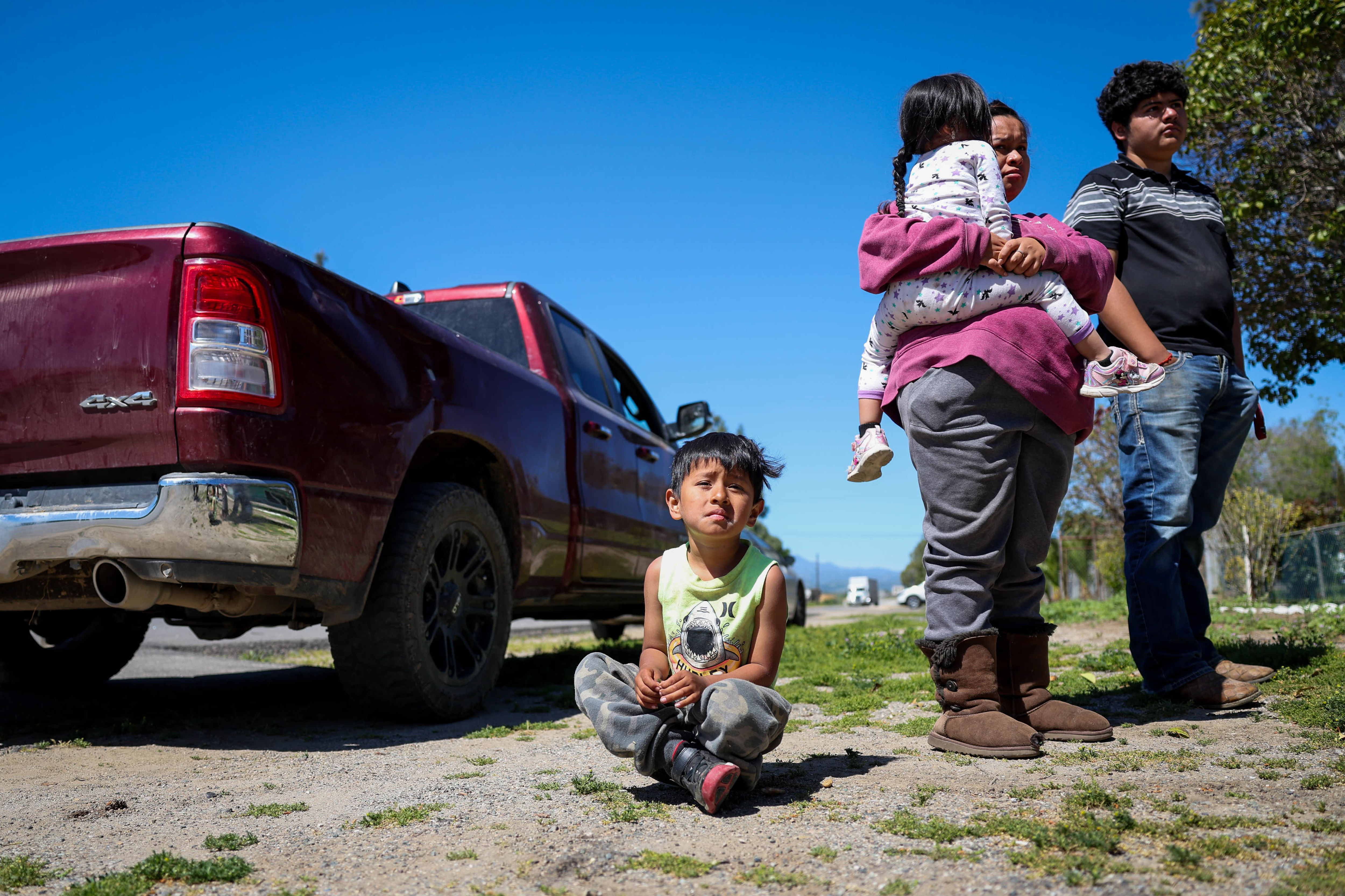Amador Velasco, 5, sits on the ground while his mother Andrea Silva talks with a neighbor after getting potable water jugs in San Lucas, Calif., on Thursday, April 14, 2023.