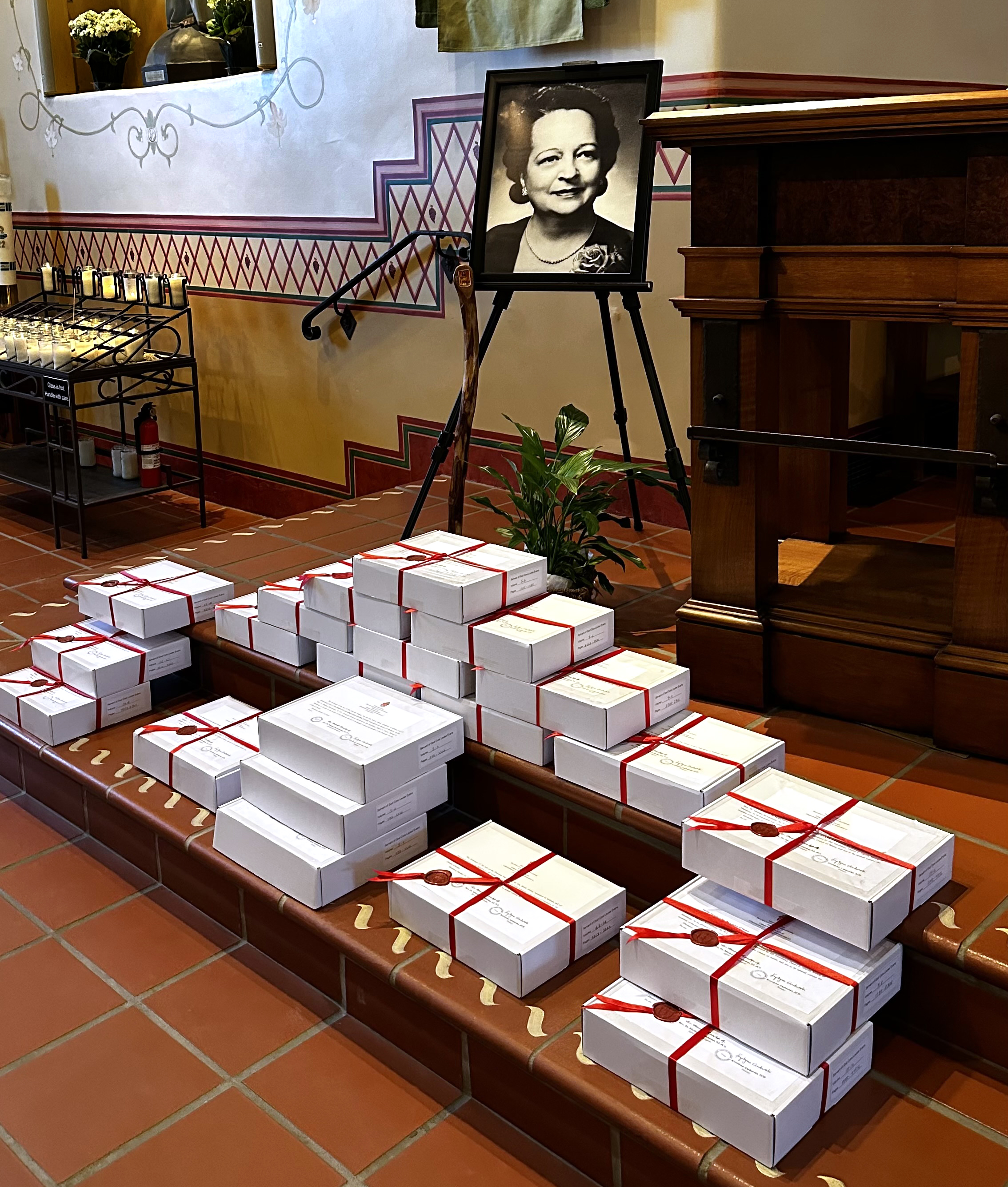 A portrait of "Servant of God" Cora Evans, who died in 1957, stands behind three sets of documents, including two copies, that support the cause for sainthood. The ceremony took place at San Carlos Cathedral in Monterey on Jan. 22, 2023. (Photo courtesy of Donita Granado)