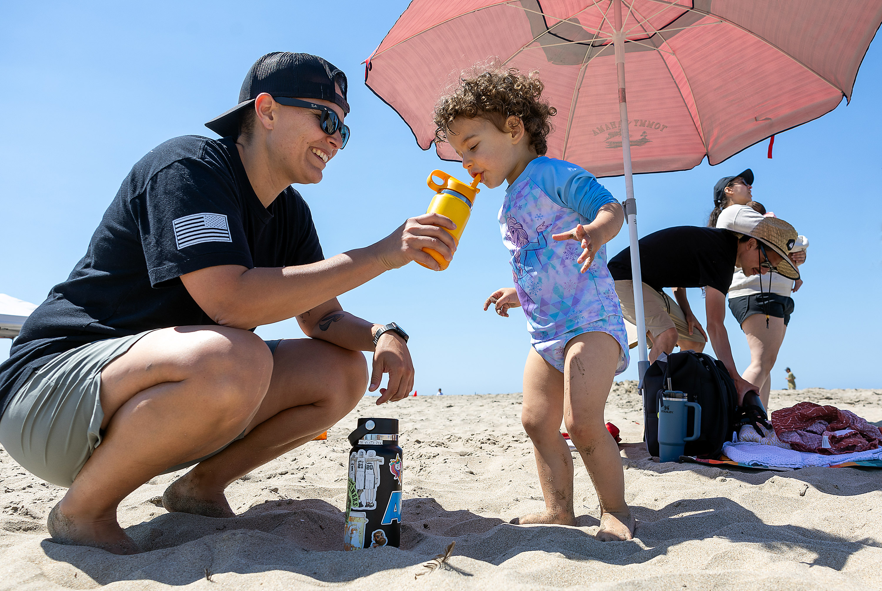 Gabby Diaz enjoys a sippy cup refreshment offered by her aunt Sarah Diaz during a family beach outing, Wednesday, July 3, 2024, in Santa Cruz, Calif. Gabby's parents, Daniel and Vanessa Diaz (back) also brought her 10-week old sister, Lily, to the beach to escape the triple digit temperatures at their home in Sunnyvale. (Karl Mondon/ Bay Area News Group)