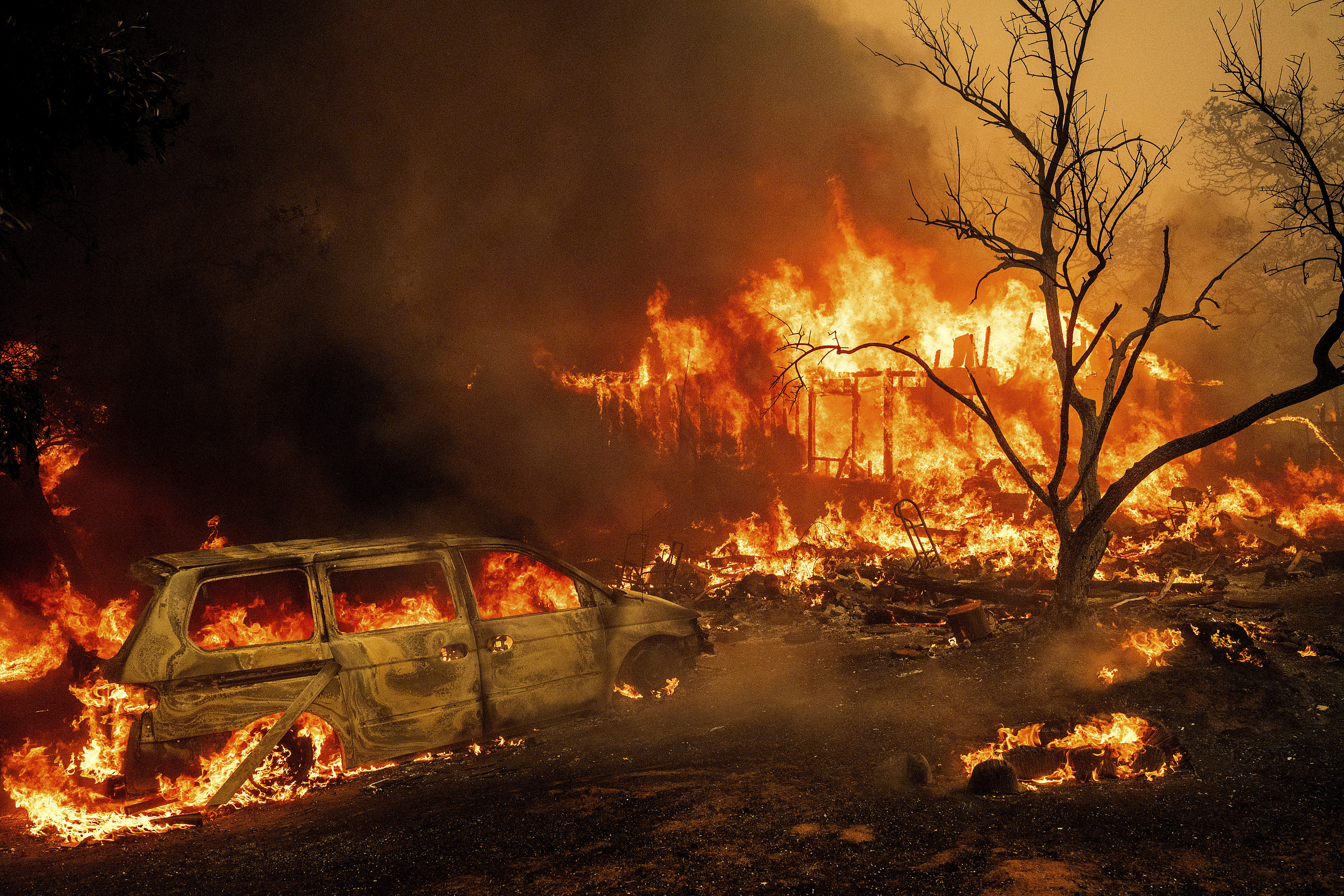 Flames consume a structure and vehicle on Bessie Lane as the Thompson Fire burns in Oroville, Calif., Tuesday, July 2, 2024. An extended heat wave blanketing Northern California has resulted in red flag fire warnings and power shutoffs. (AP Photo/Noah Berger)