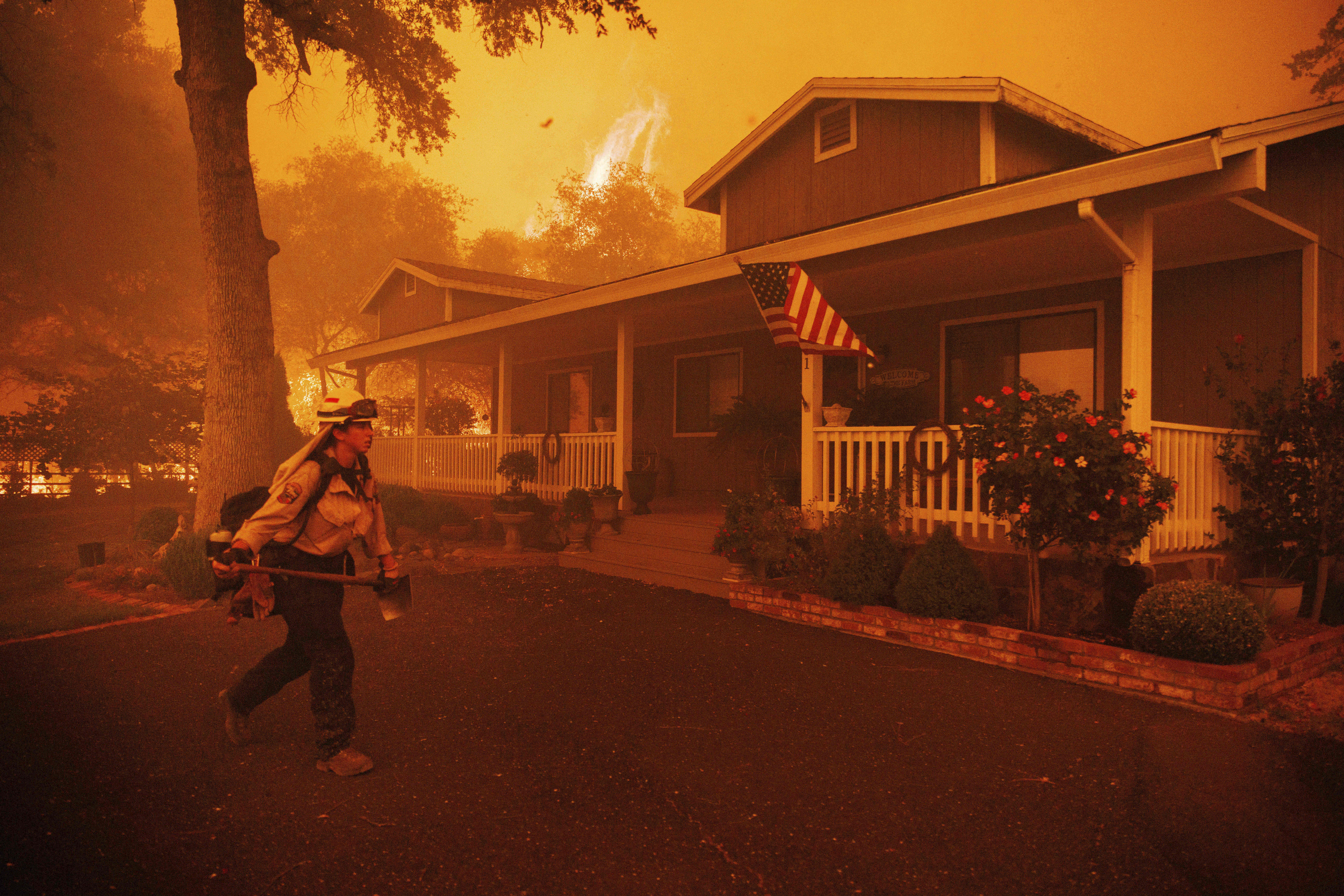 A firefighter works to protect a structure as the Thompson Fire approaches, Tuesday, July 2, 2024, in Oroville, Calif. (AP Photo/Ethan Swope)
