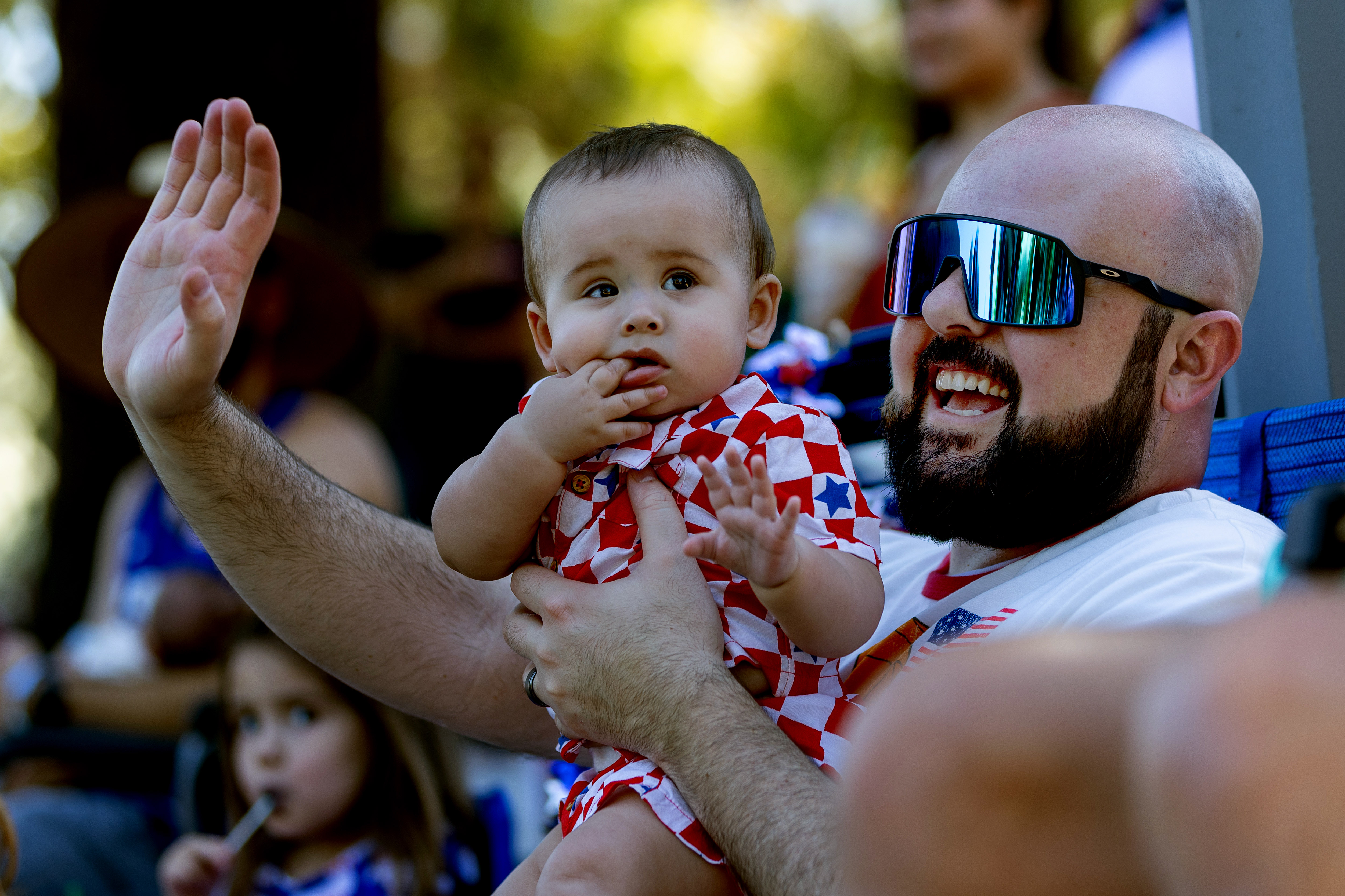 Scott Healy and his newborn Brixton wave to participants marching in the Rose, White and Blue 4th of July Parade in San Jose, Calif., Thursday, July 4, 2024. (Karl Mondon/ Bay Area News Group)