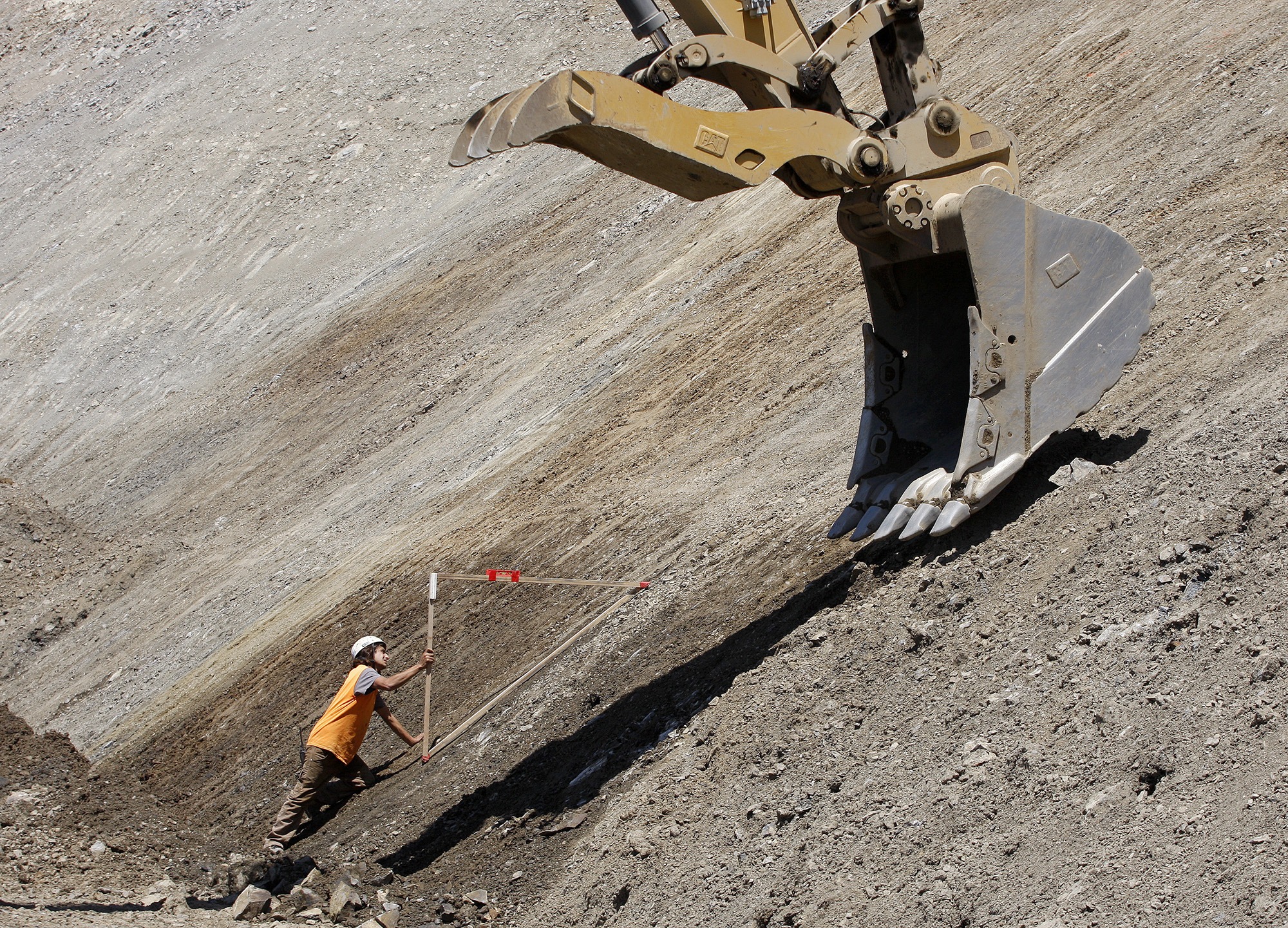Jesse Foster uses a 45-degree form to monitor the work being done by a heavy machine operator as work continues at the Mud Creek slide on Highway 1 south of Big Sur on May 7, 2018.