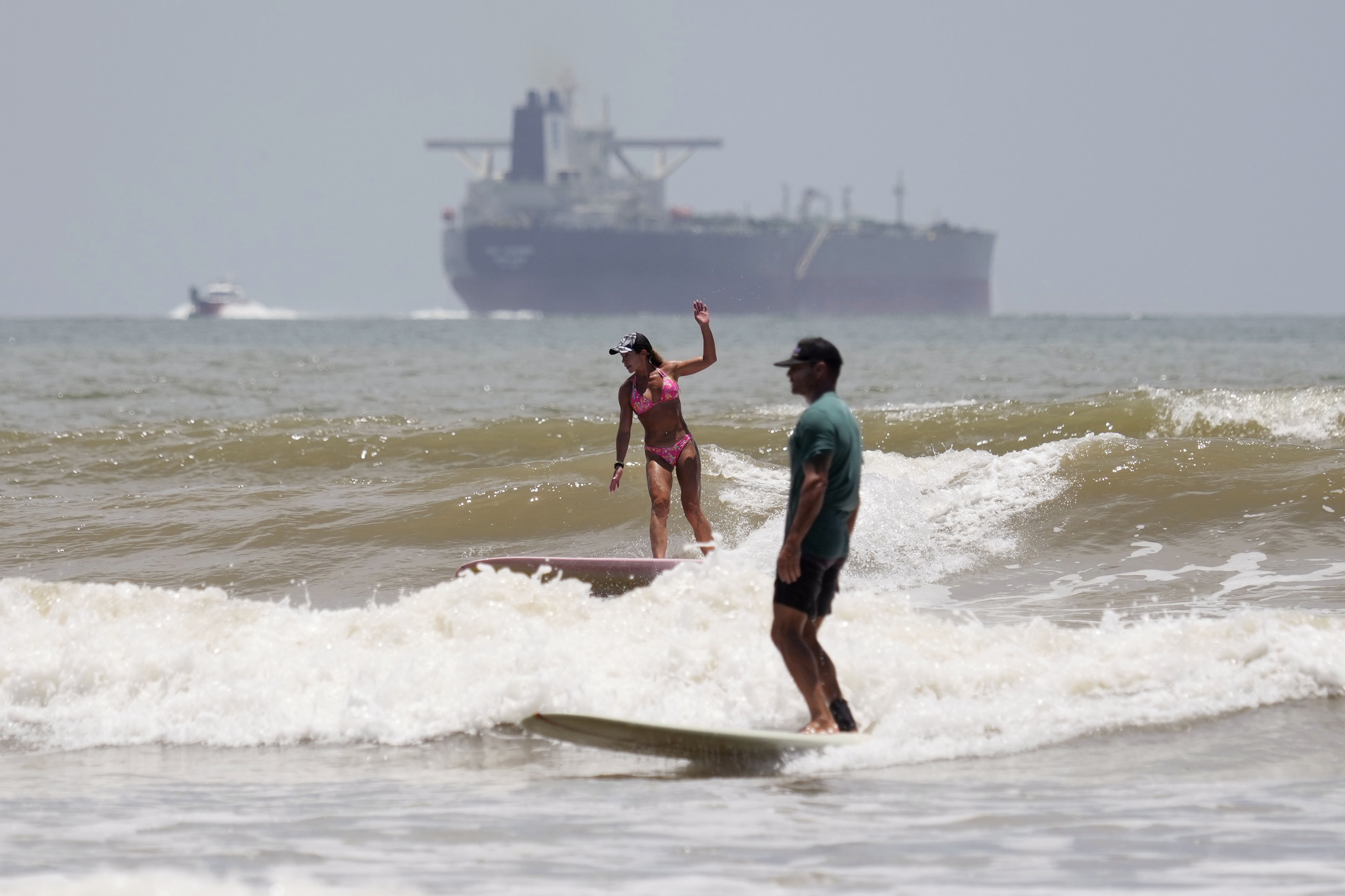 An oil tanker heads out to open water as surfers take advantage of waves ahead of Hurricane Beryl's arrival in Port Aransas, Texas, Saturday, July 6, 2024. (AP Photo/Eric Gay)