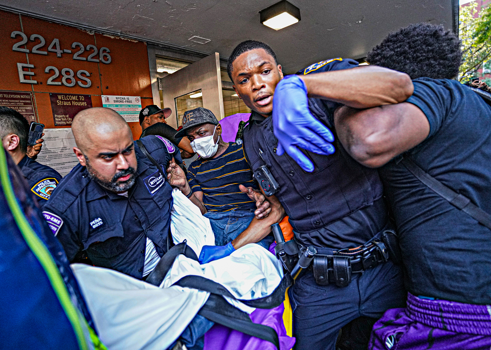 Police take a man into custody on a stretcher, as an angry mob tries to get at him, Monday, July 8, 2024, in Manhattan, New York. (Photo by Dean Moses / amNewYork)