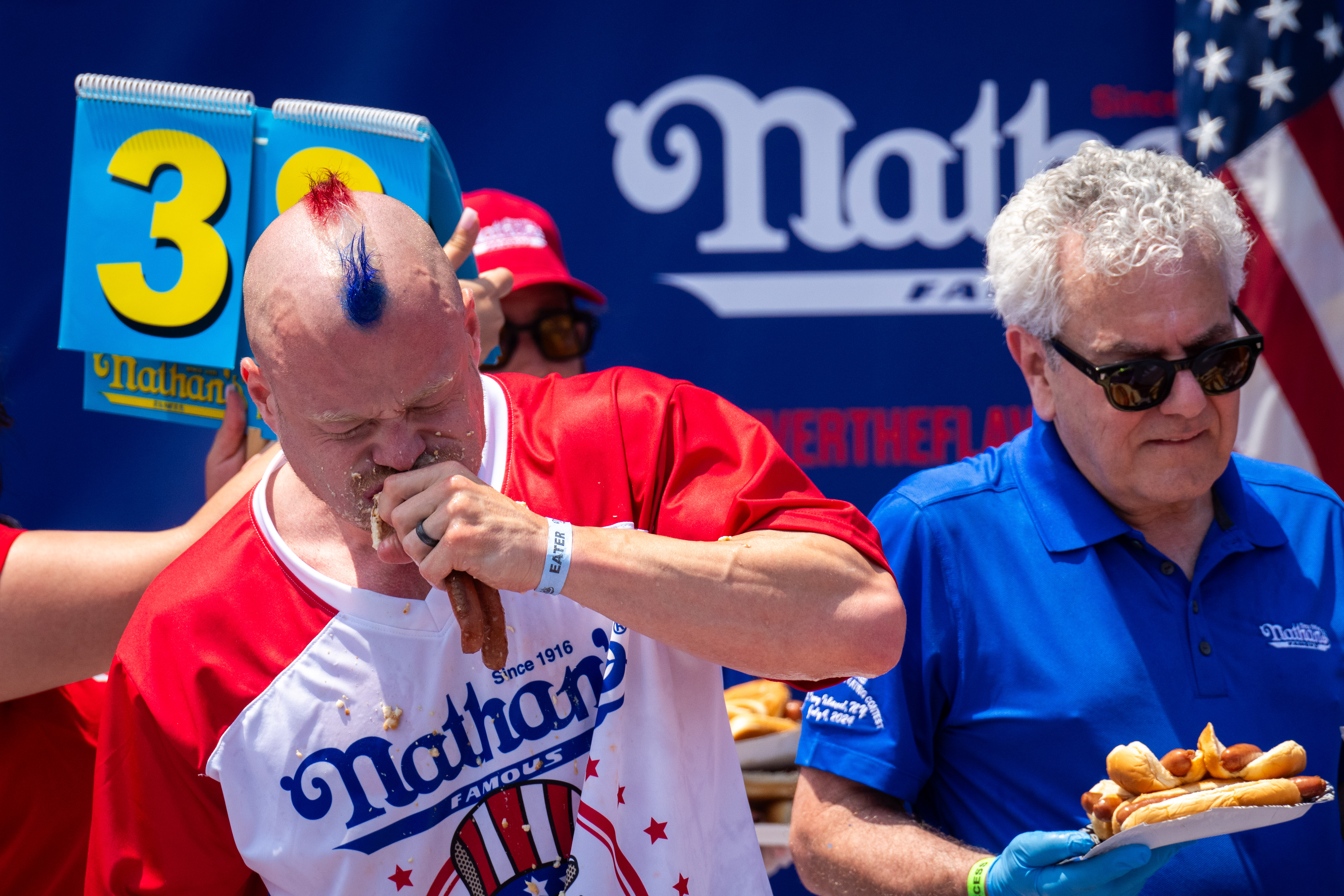 NEW YORK, NEW YORK - JULY 4: Participants compete for the mens title at Nathan's Annual Hot Dog Eating Contest on July 4, 2024 in New York City. Sixteen-time winner Joey Chestnut is banned from this year's contest due to his partnership with Nathan's competitor Impossible Foods, which sells plant-based hot dogs. (Photo by Adam Gray/Getty Images)