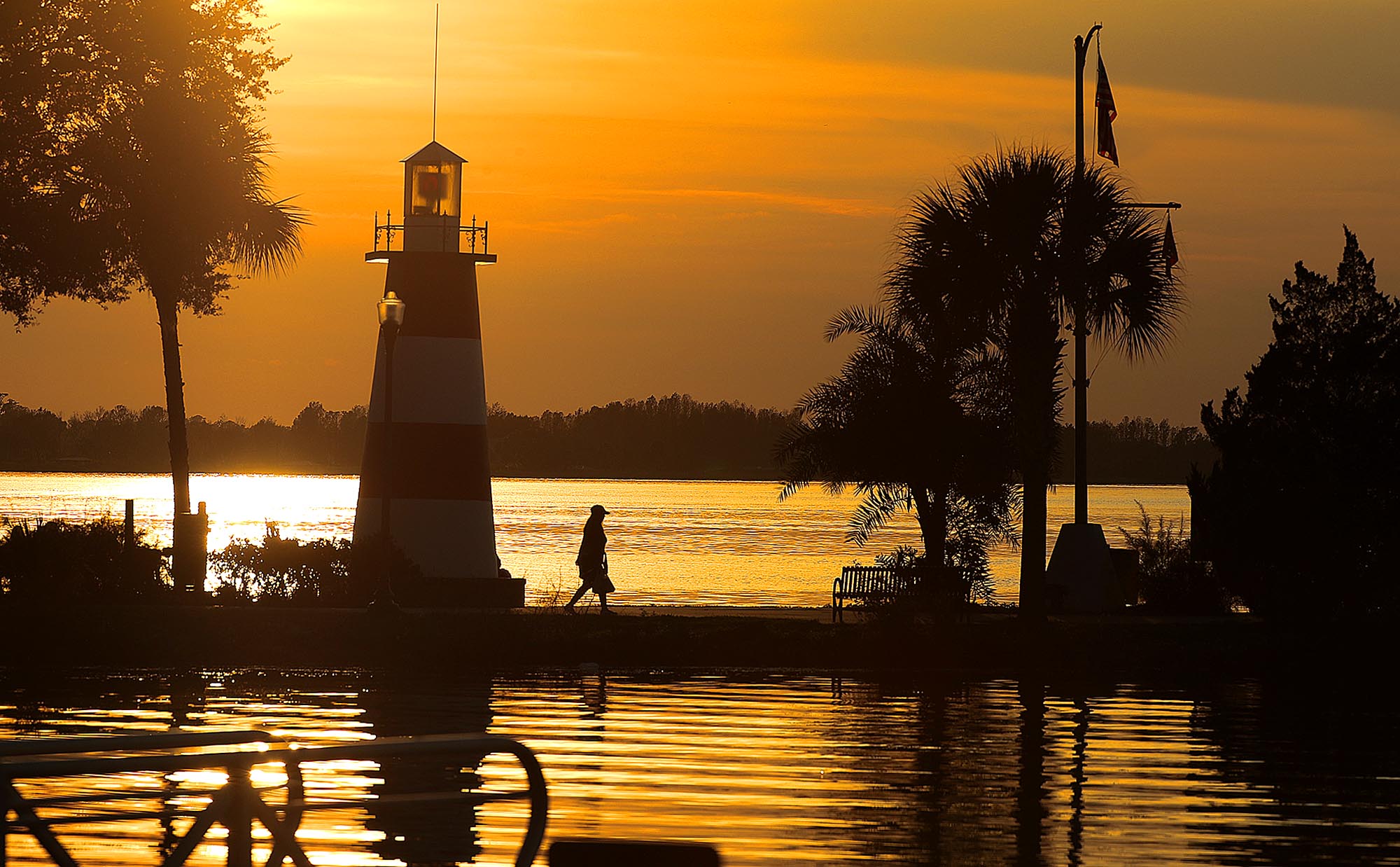 A stroller walks by the Mount Dora Lighthouse as the sun sets on Lake Dora in Mount Dora on Thursday, Jan. 2, 2020. (Stephen M. Dowell/Orlando Sentinel)