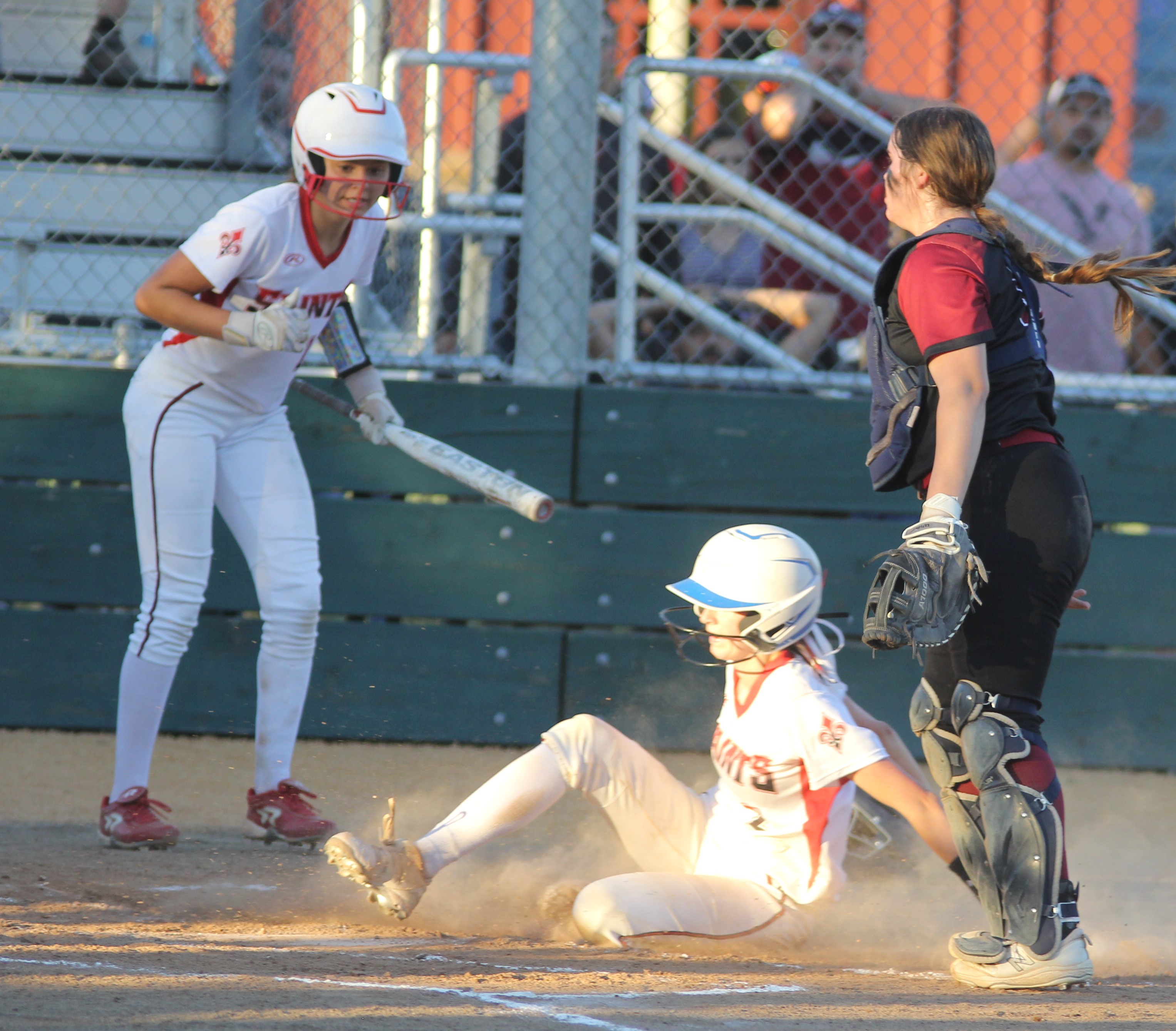St. Helena's Sofia Cupp slides home with the first run of the game in the bottom of the third as teammate Aribella Farrell and Clear Lake catcher Hailee Bussard look on.
